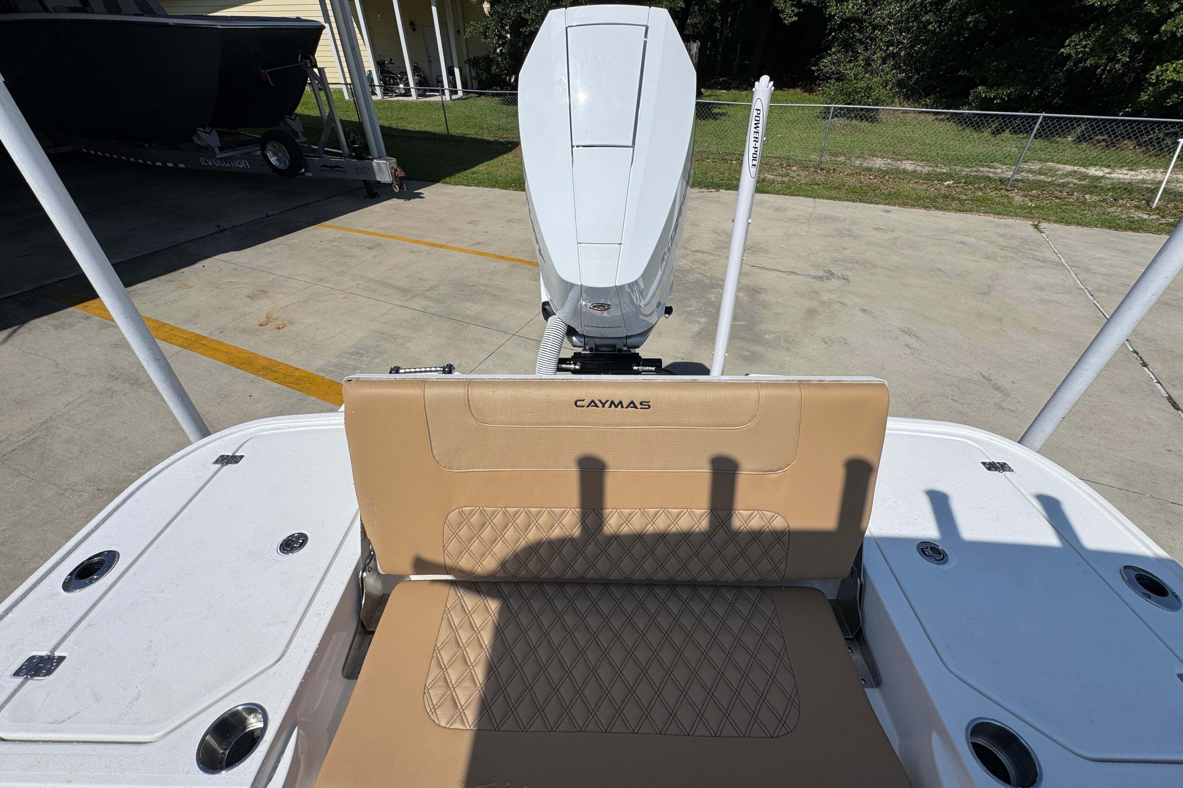 2027 Caymas 26 HB boat with tan seating and outboard motor in a driveway.