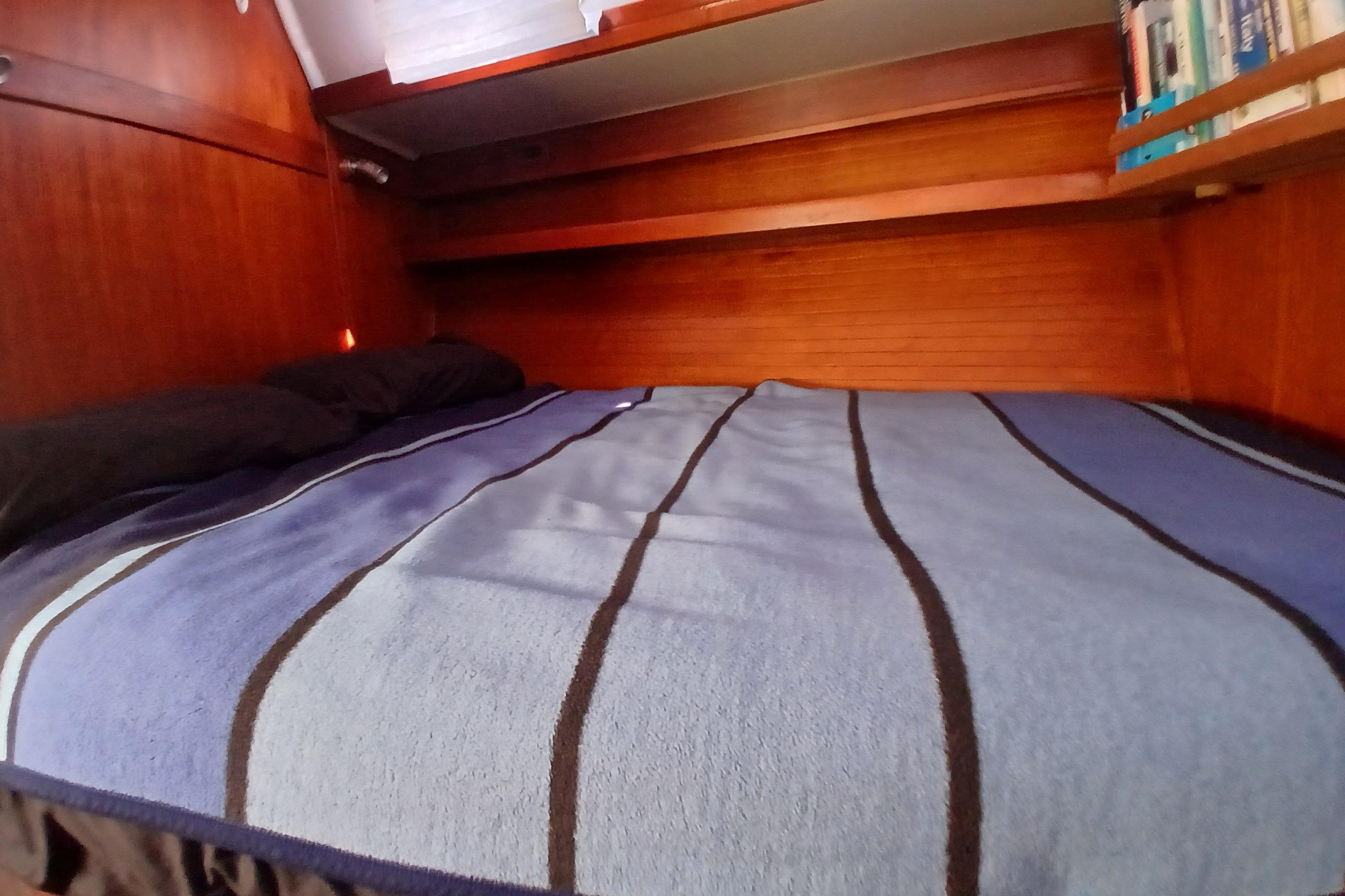 Cozy cabin interior of 1995 Catalina 42 MkII sailboat with striped bedding and wooden shelves.