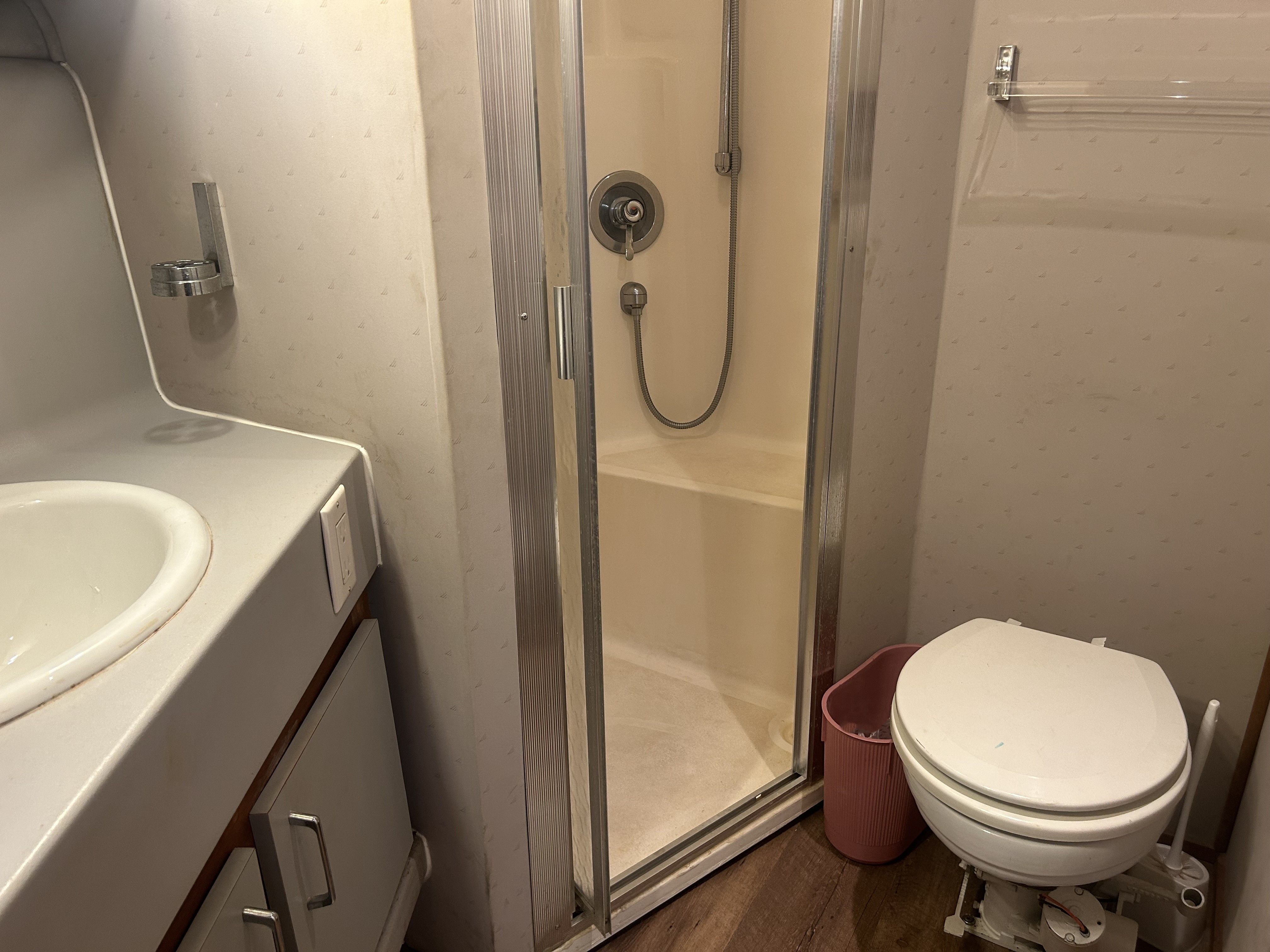 The image shows a boat bathroom with a shower, sink, and toilet.