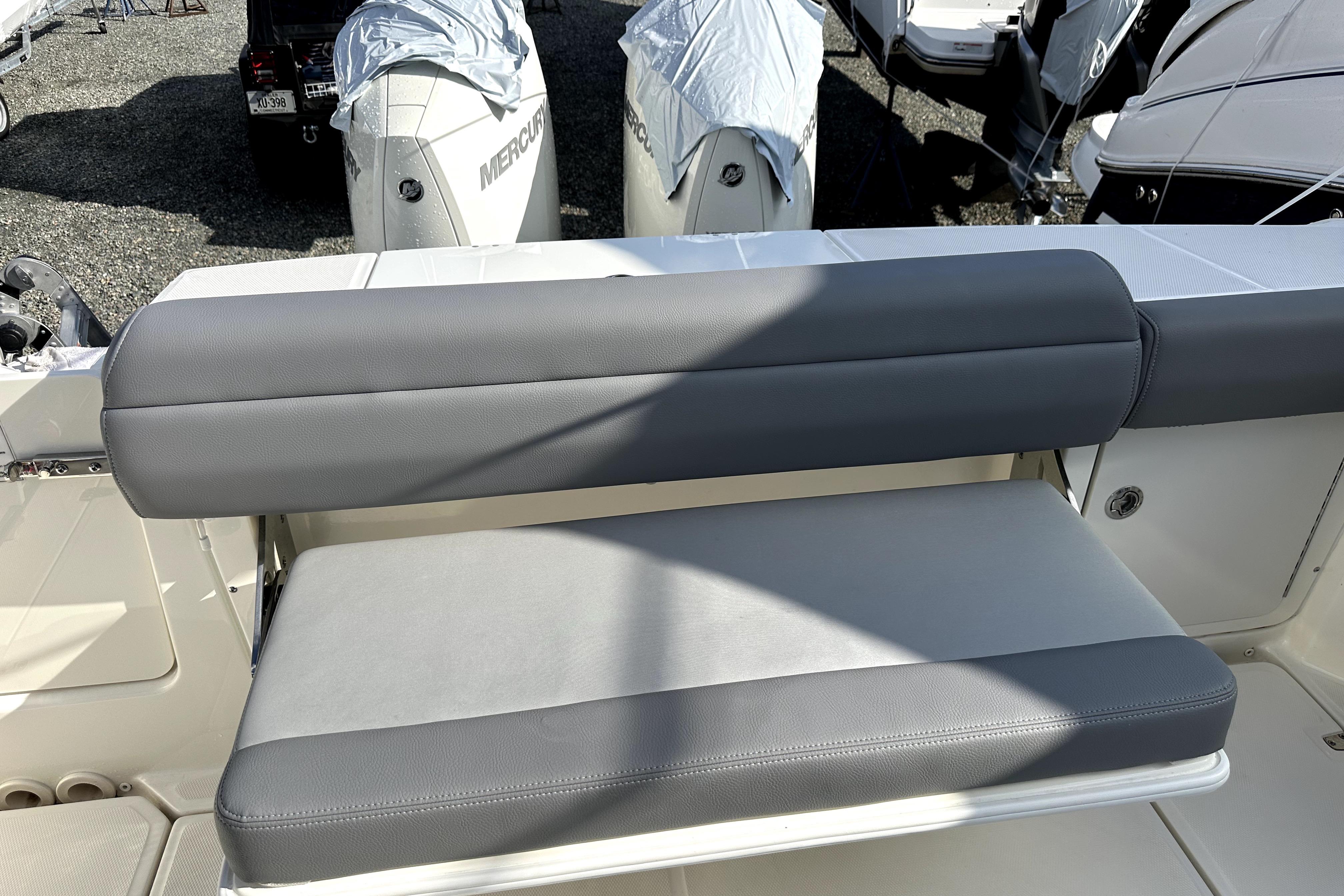 2023 Boston Whaler OUTRAGE boat seat with gray upholstery, docked with covered engines.