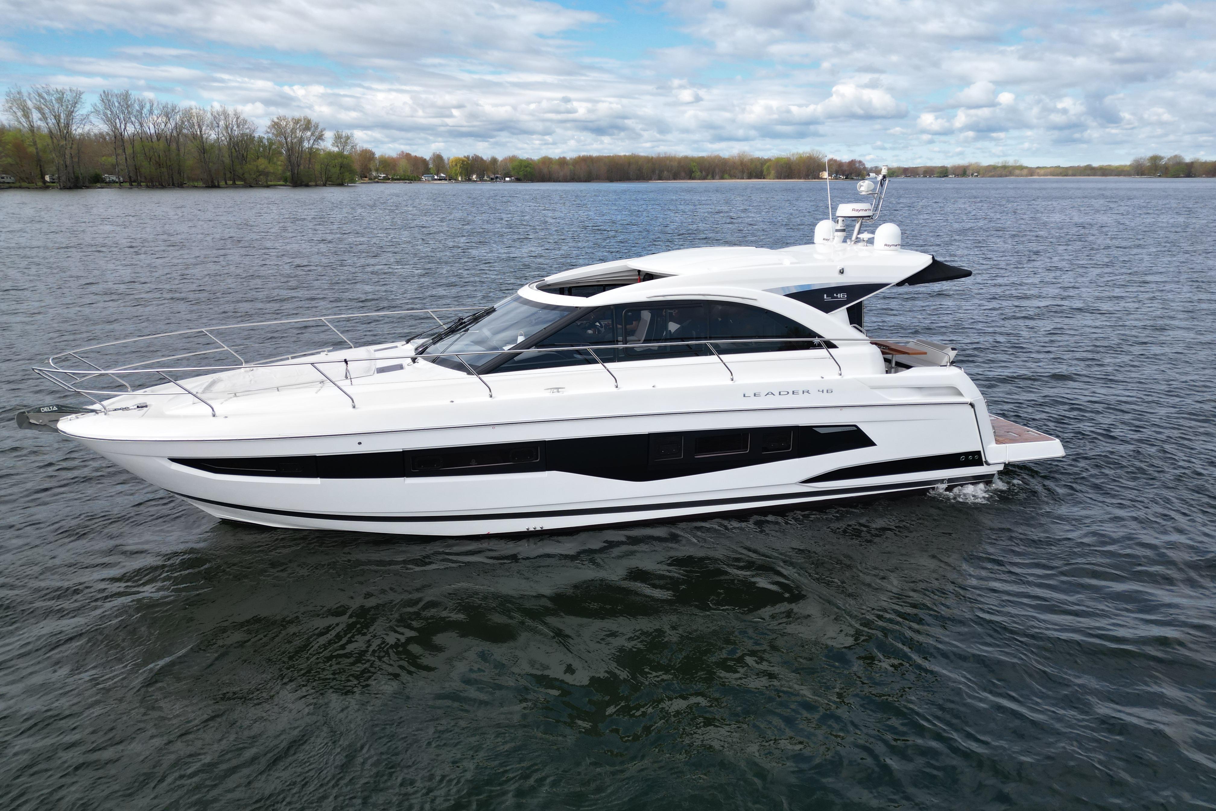 2022 Jeanneau Leader 46 yacht cruising on a serene lake under a partly cloudy sky.