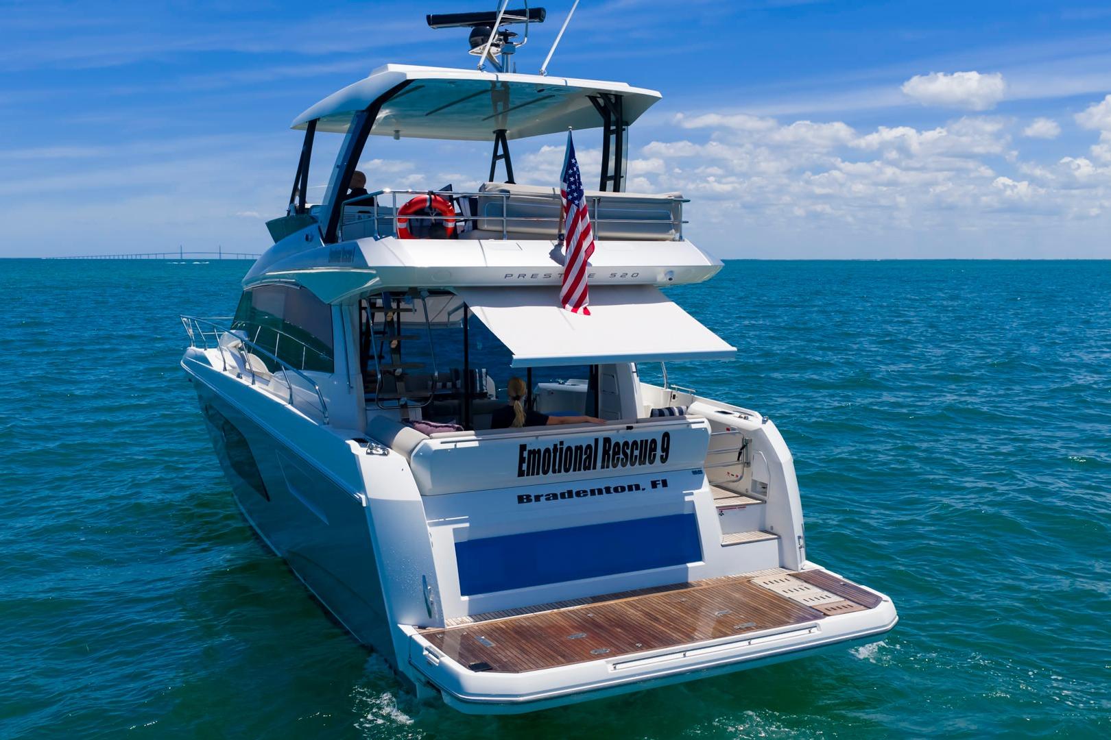 Luxury 2022 Prestige 520 yacht cruising in open sea with American flag.