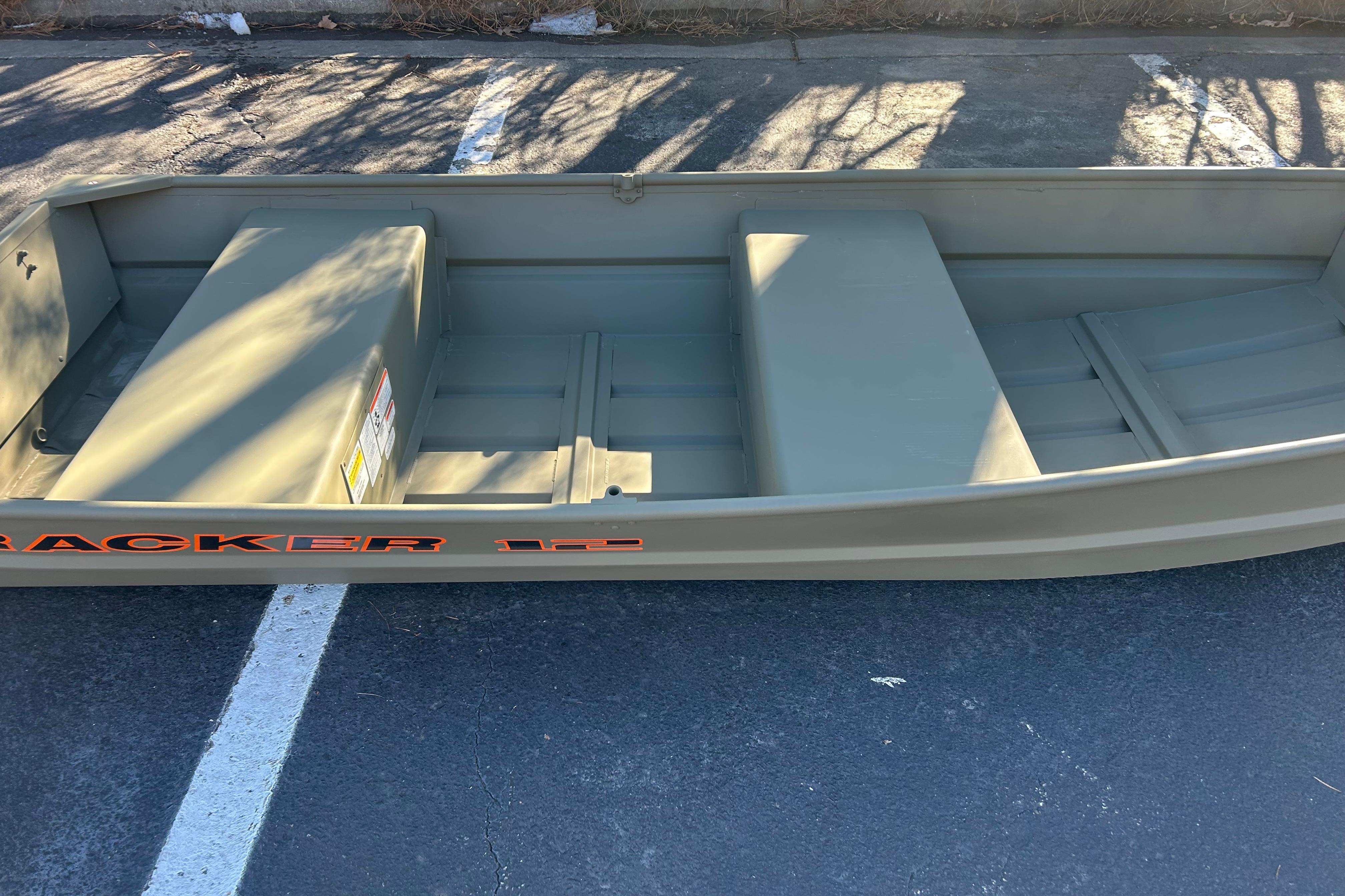 2026 Tracker Grizzly 12 Jon boat on pavement, showcasing interior seating and storage.