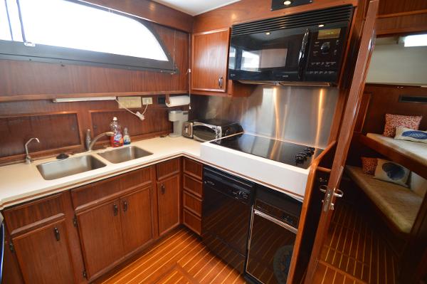 The 1980 Hatteras 53 Yacht Fisherman kitchen features wooden cabinets, a sink, and modern appliances.