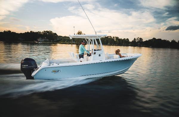 2024 Sea Hunt Ultra 234 boat cruising on a calm lake at sunset.