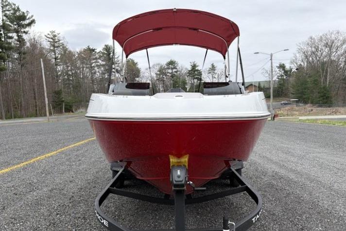 Red 2026 Tahoe T21 boat on trailer, parked outdoors with trees in background.