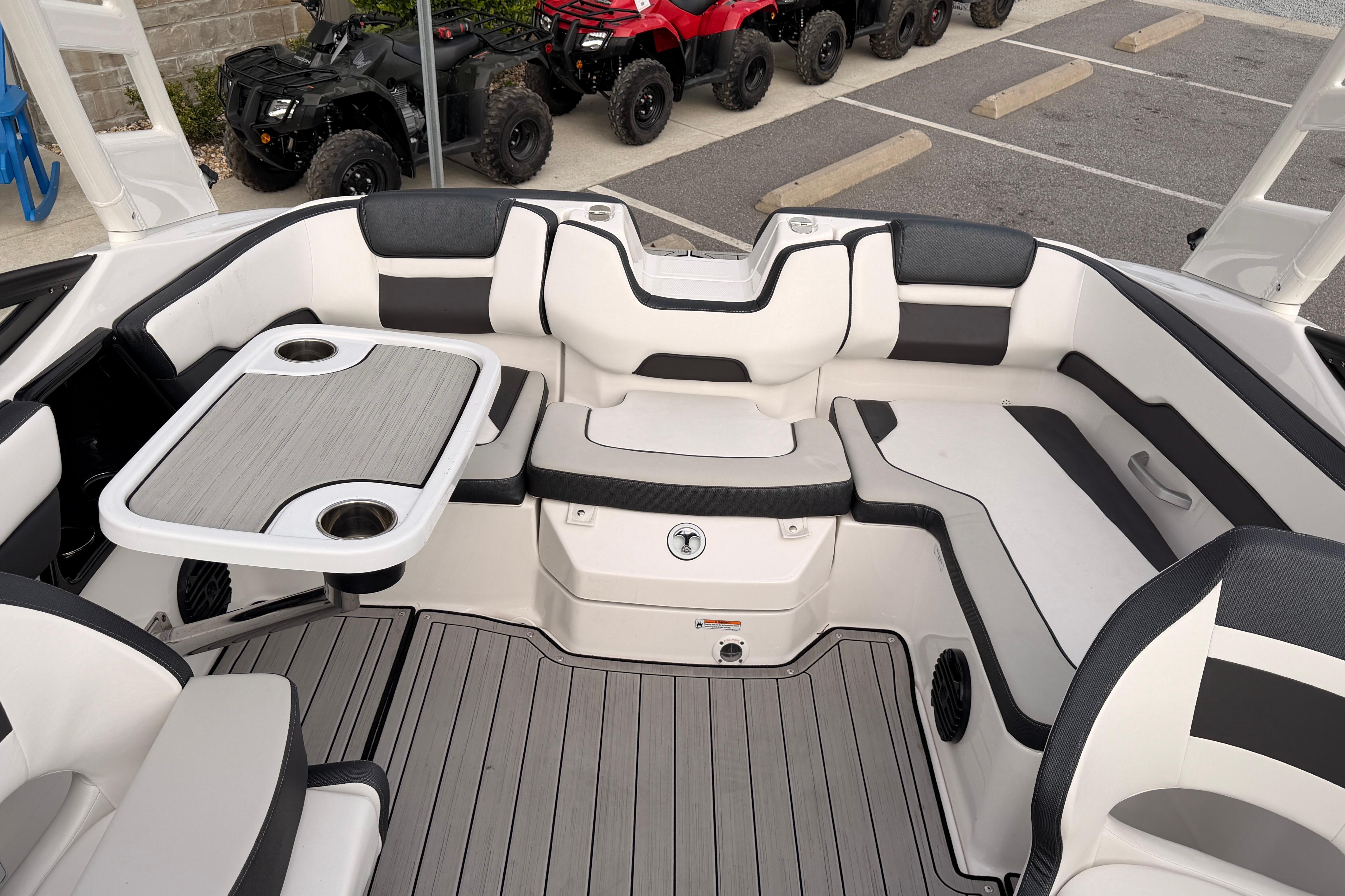 2023 Yamaha 195S boat interior with seating and table, parked near ATVs.