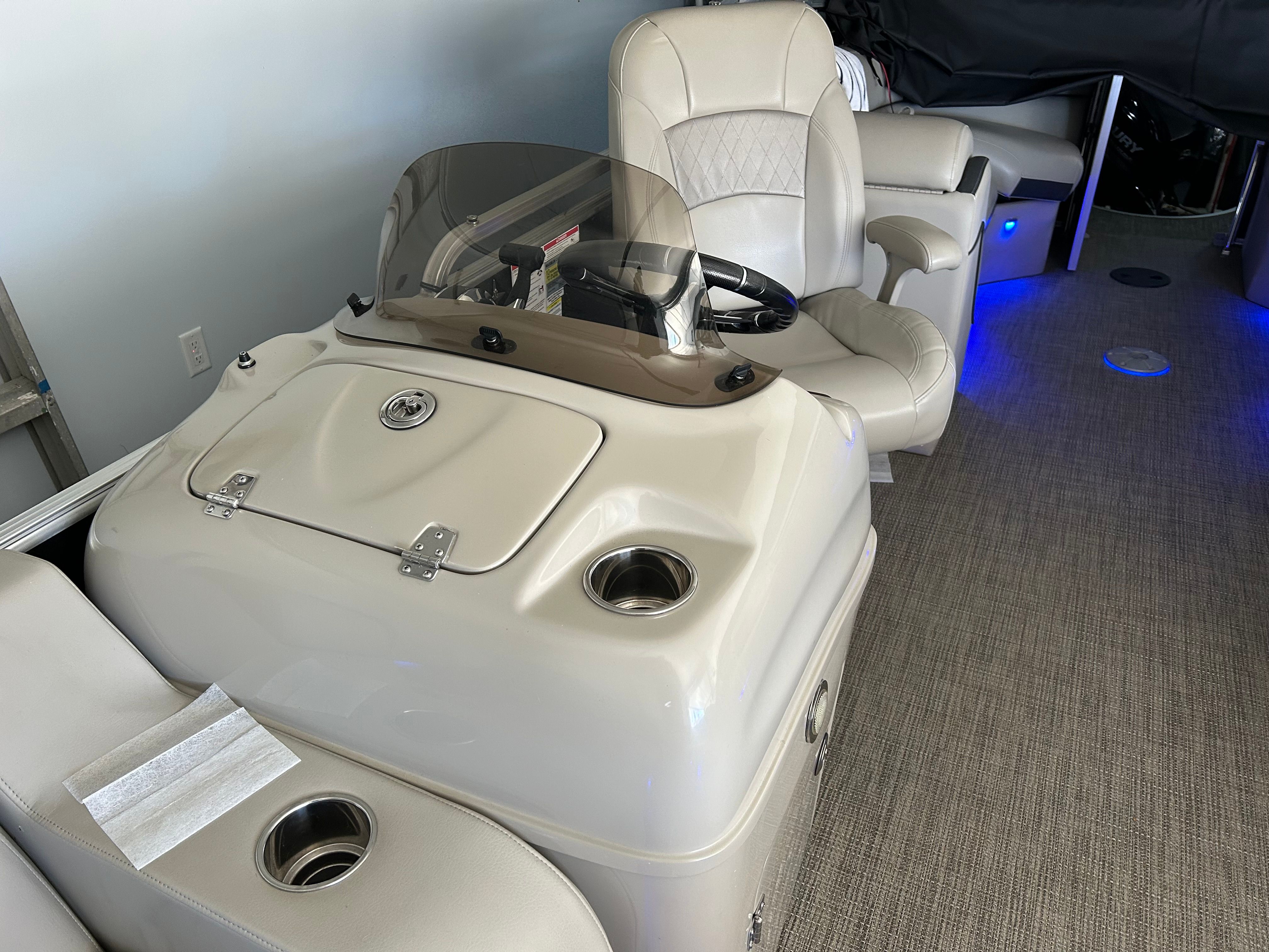 Interior of a boat with beige seats and a helm station.