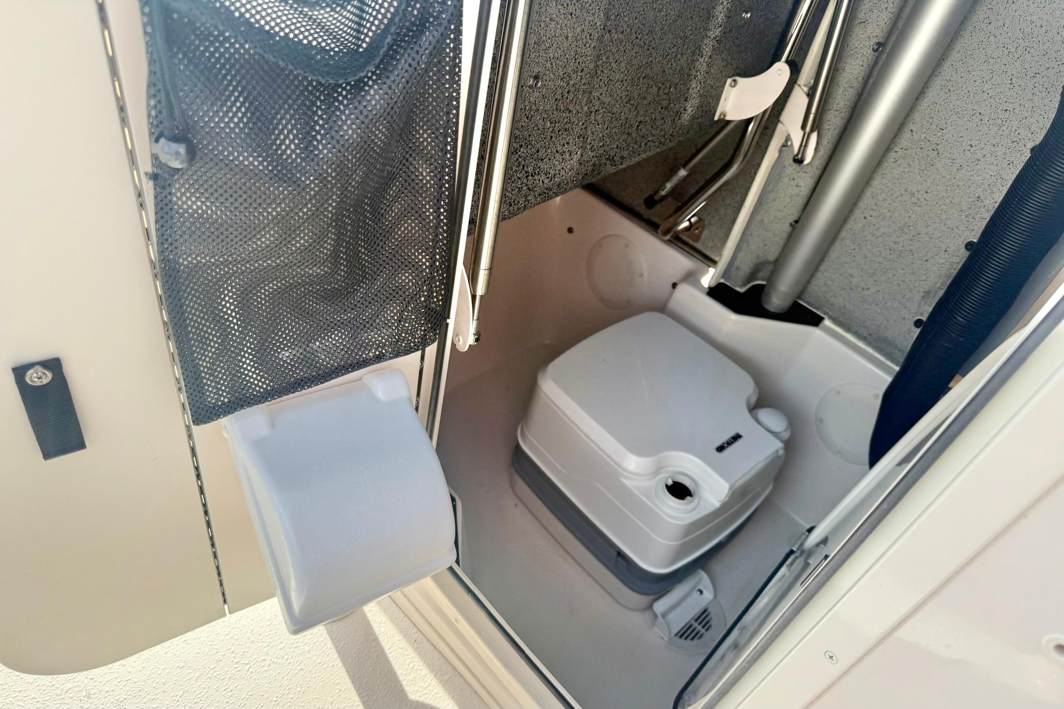 Interior of 2026 Carolina Skiff 24 Ultra Elite boat with compact marine toilet.