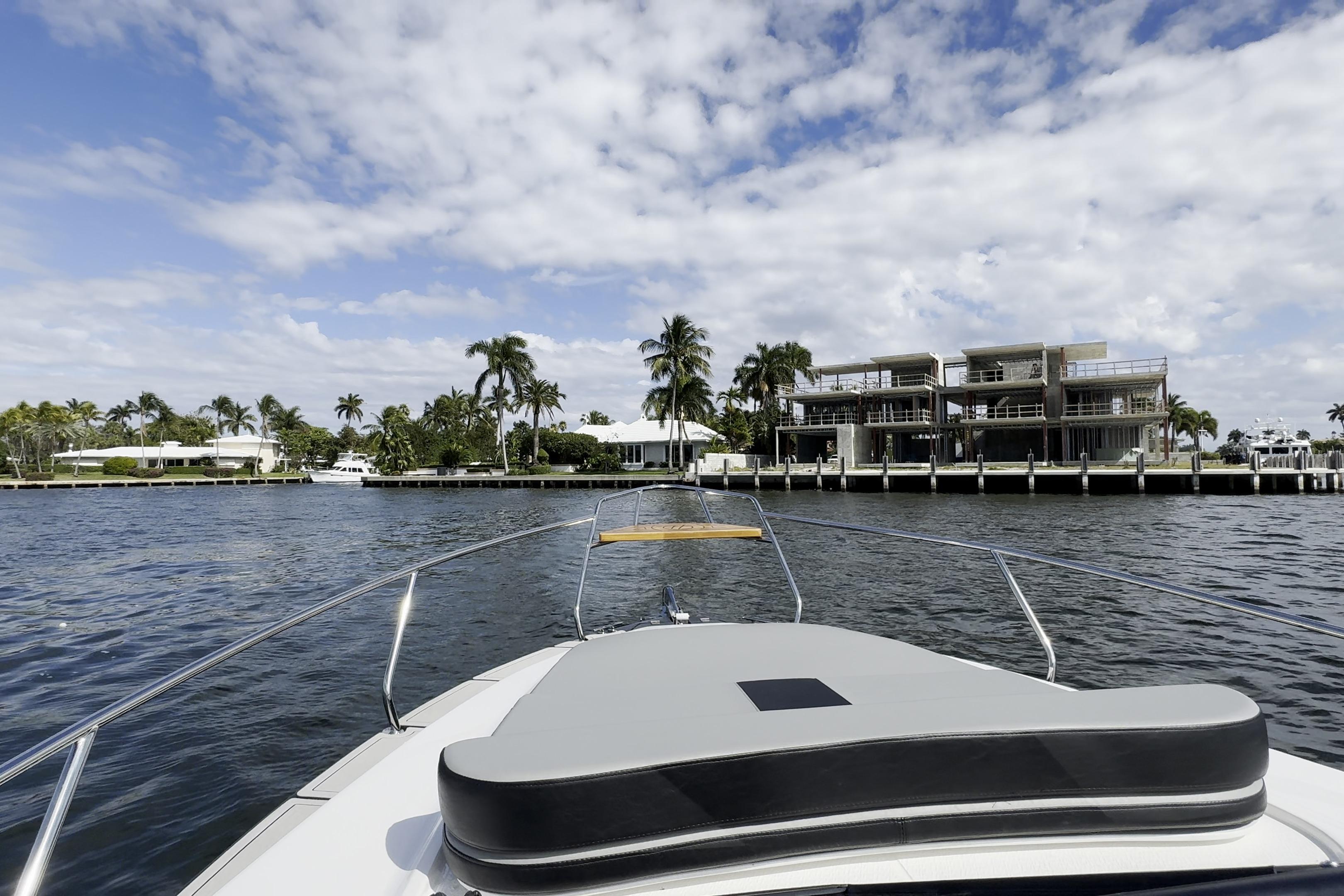 Bow view from Hanover 305 yacht, 2027 model, cruising near waterfront homes and palm trees.
