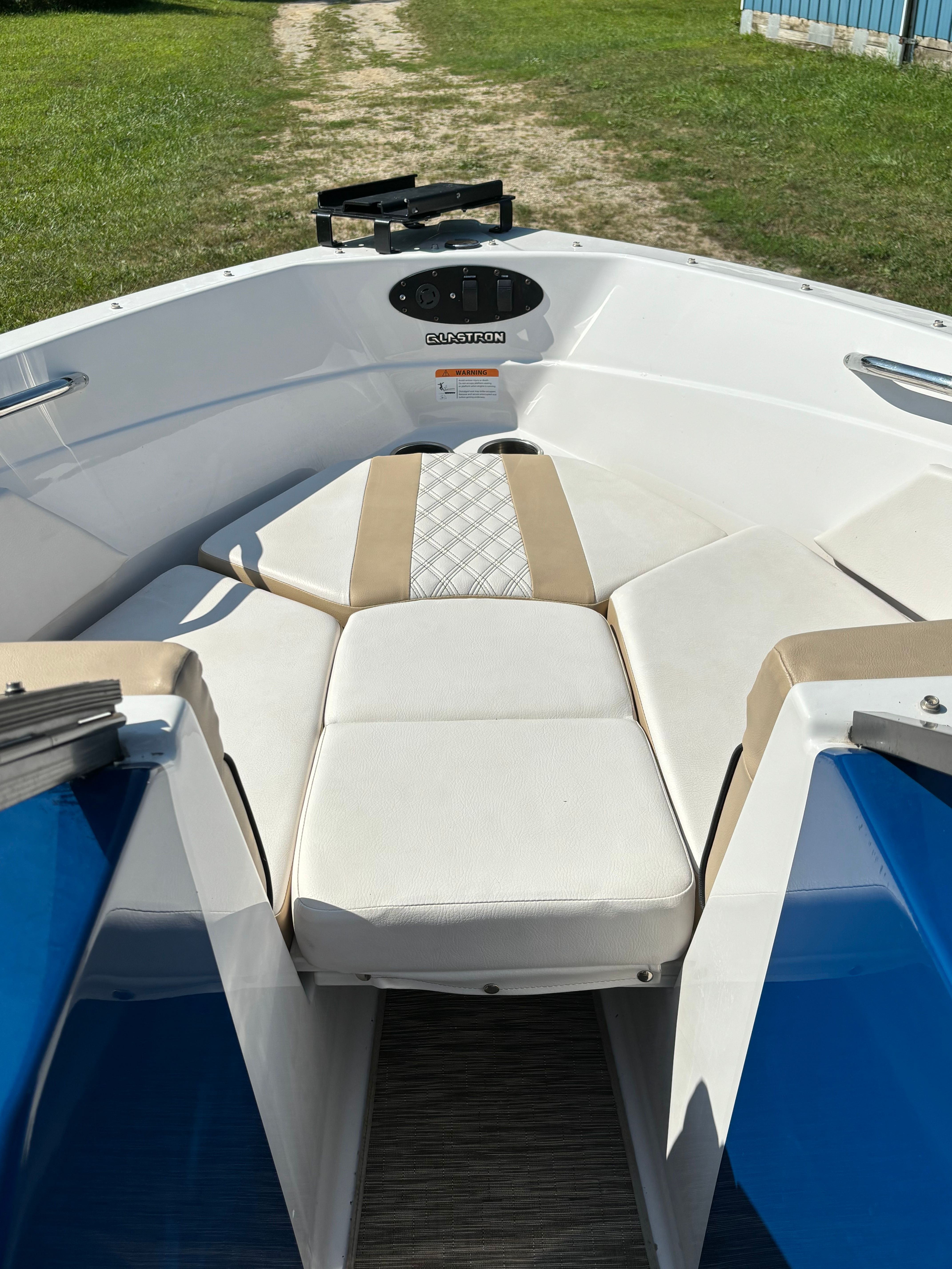The boat features white and beige upholstery with blue accents, situated on dry land.