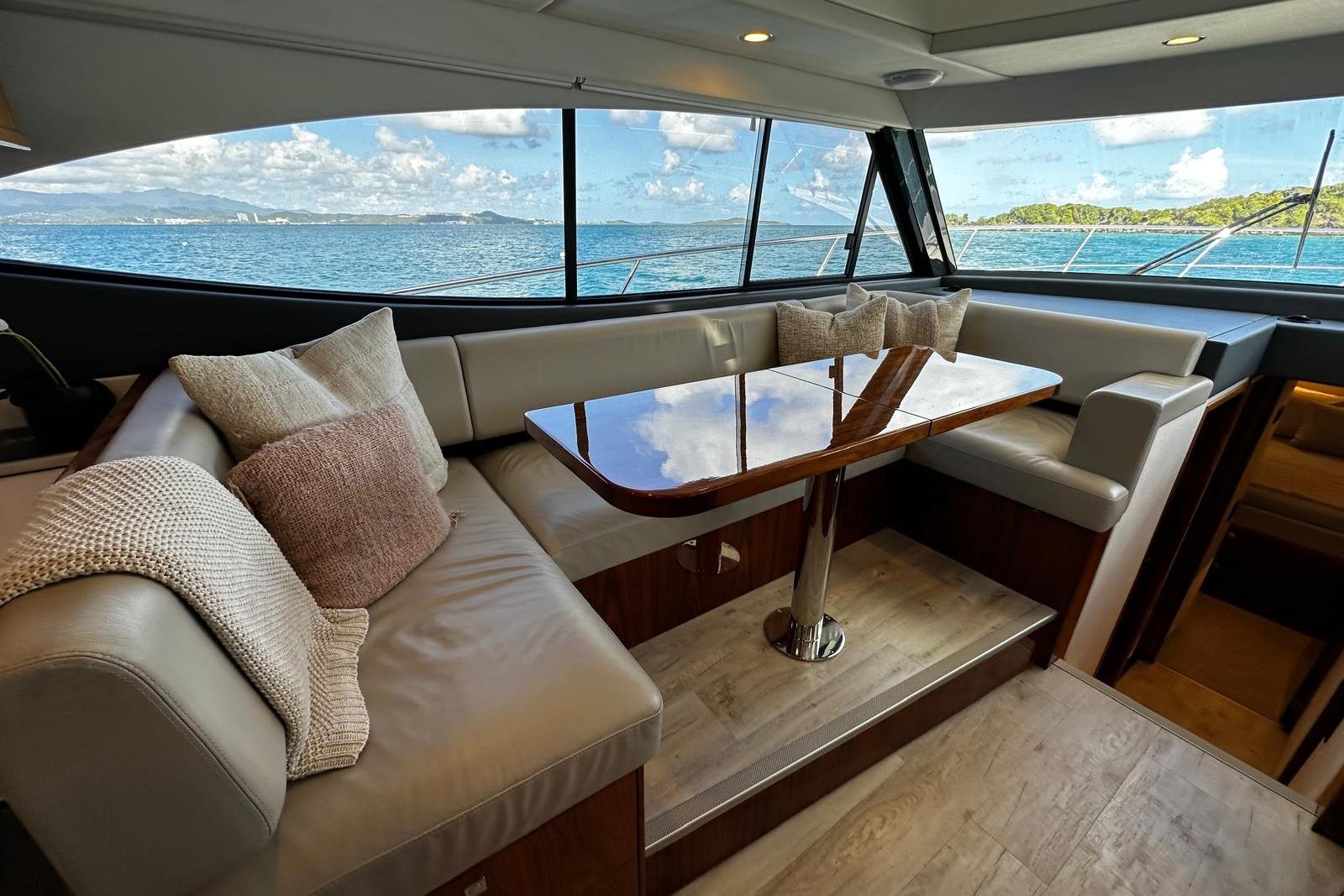 Luxurious interior of 2023 Riviera 465 SUV yacht with ocean view through large windows.