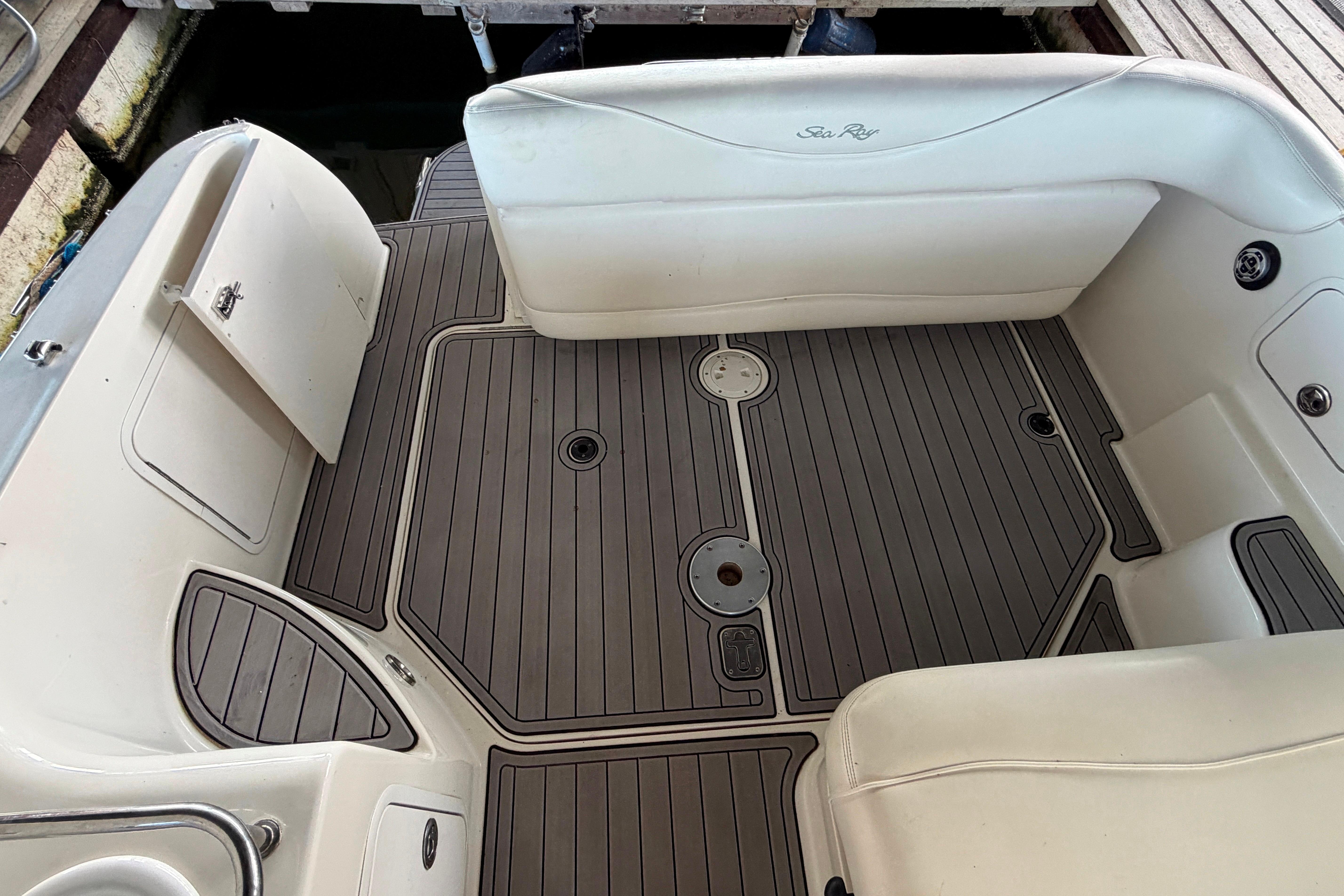 2004 Sea Ray Sundancer 260 boat interior with cushioned seating and wood-patterned flooring.