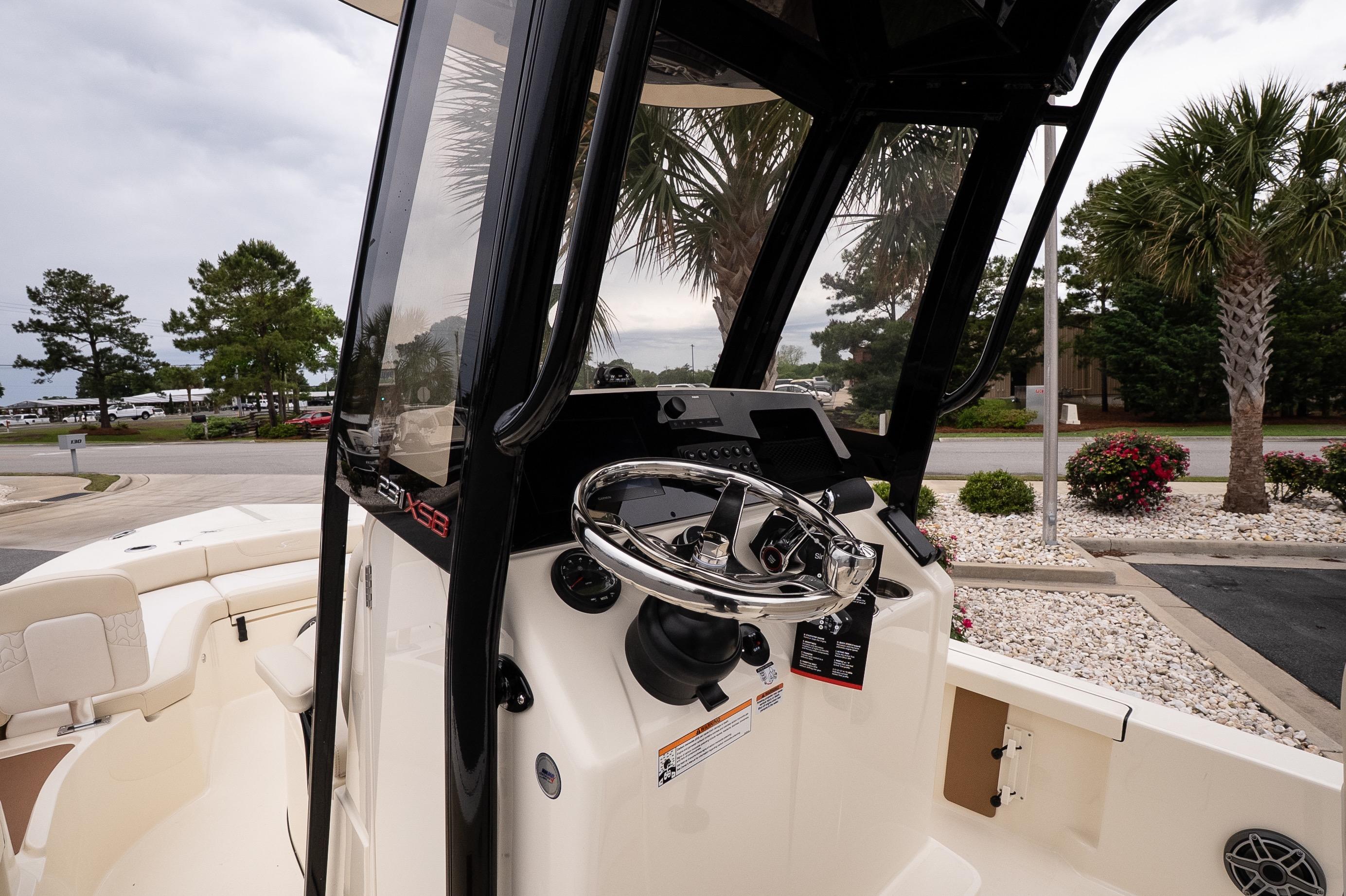 2026 Scout 231 XSB boat cockpit with steering wheel and console, surrounded by palm trees.