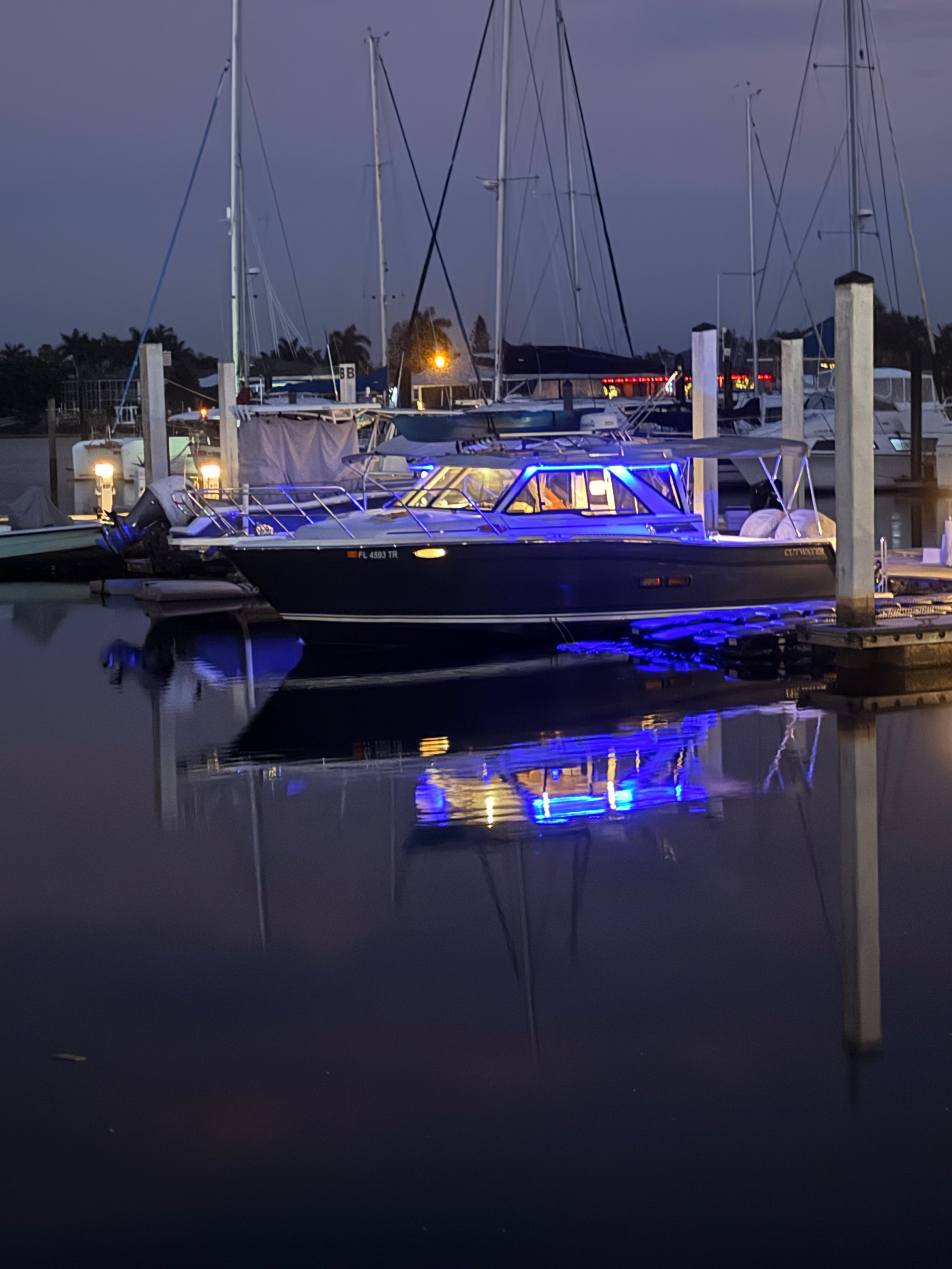 A 2023 Cutwater C-228 boat docked at night, illuminated by blue lights.