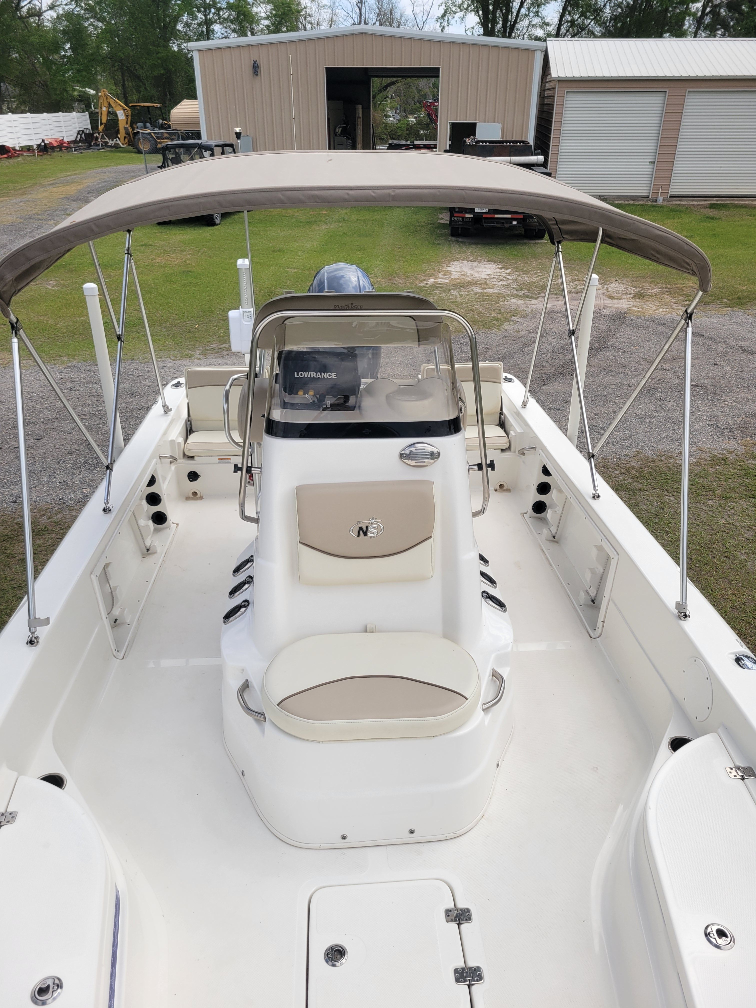 A white boat with a sunshade is on dry land.