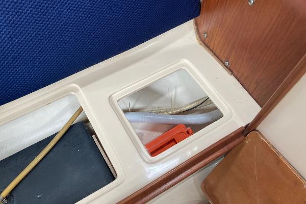 Interior view of a 1989 Catalina 30 sailboat showing storage compartment and seating area.