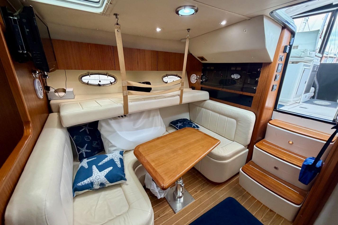 Interior of 2003 Tiara Yachts 3500 Open, featuring cozy seating and wooden table.