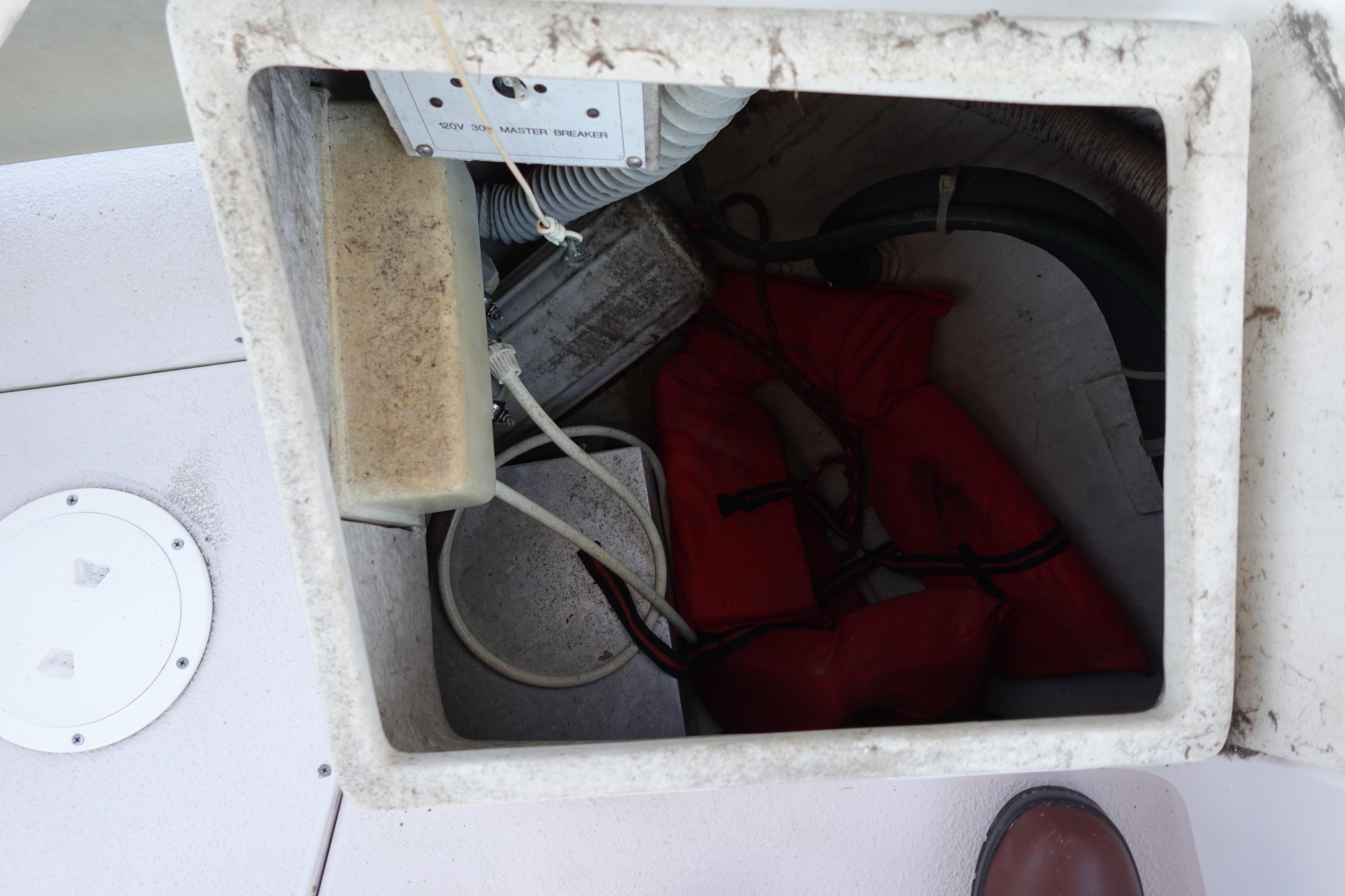 Storage compartment on a 1997 Catalina 28 boat with life jackets and electrical components.