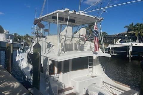 1987 Topaz 44 Flybridge yacht docked, featuring a spacious deck and American flag.