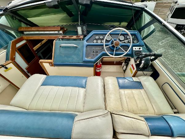 1987 Sea Ray 270 Sundancer boat interior with blue and white seating, steering wheel, and control panel.