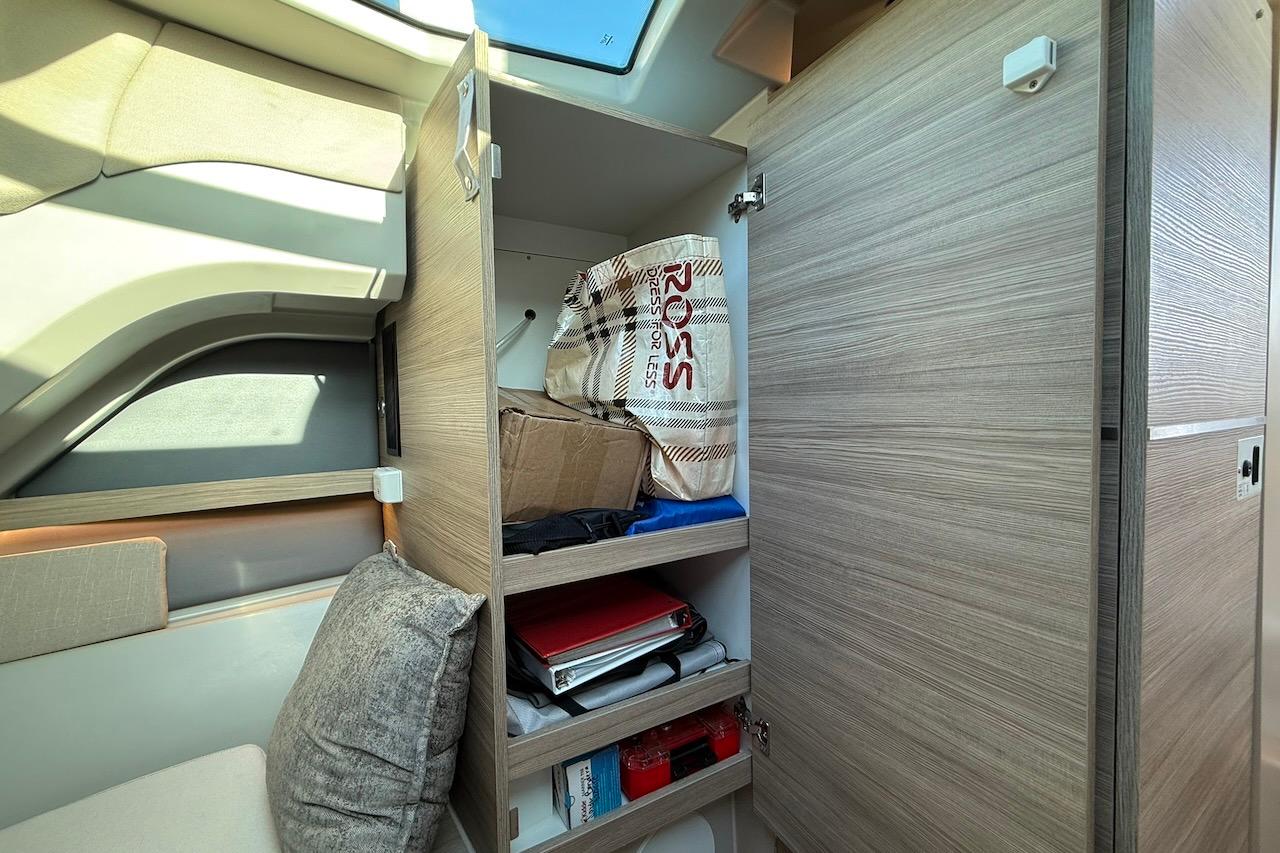 Interior storage of 2024 Saxdor 320 GTC boat with open wooden cabinet and shelves.