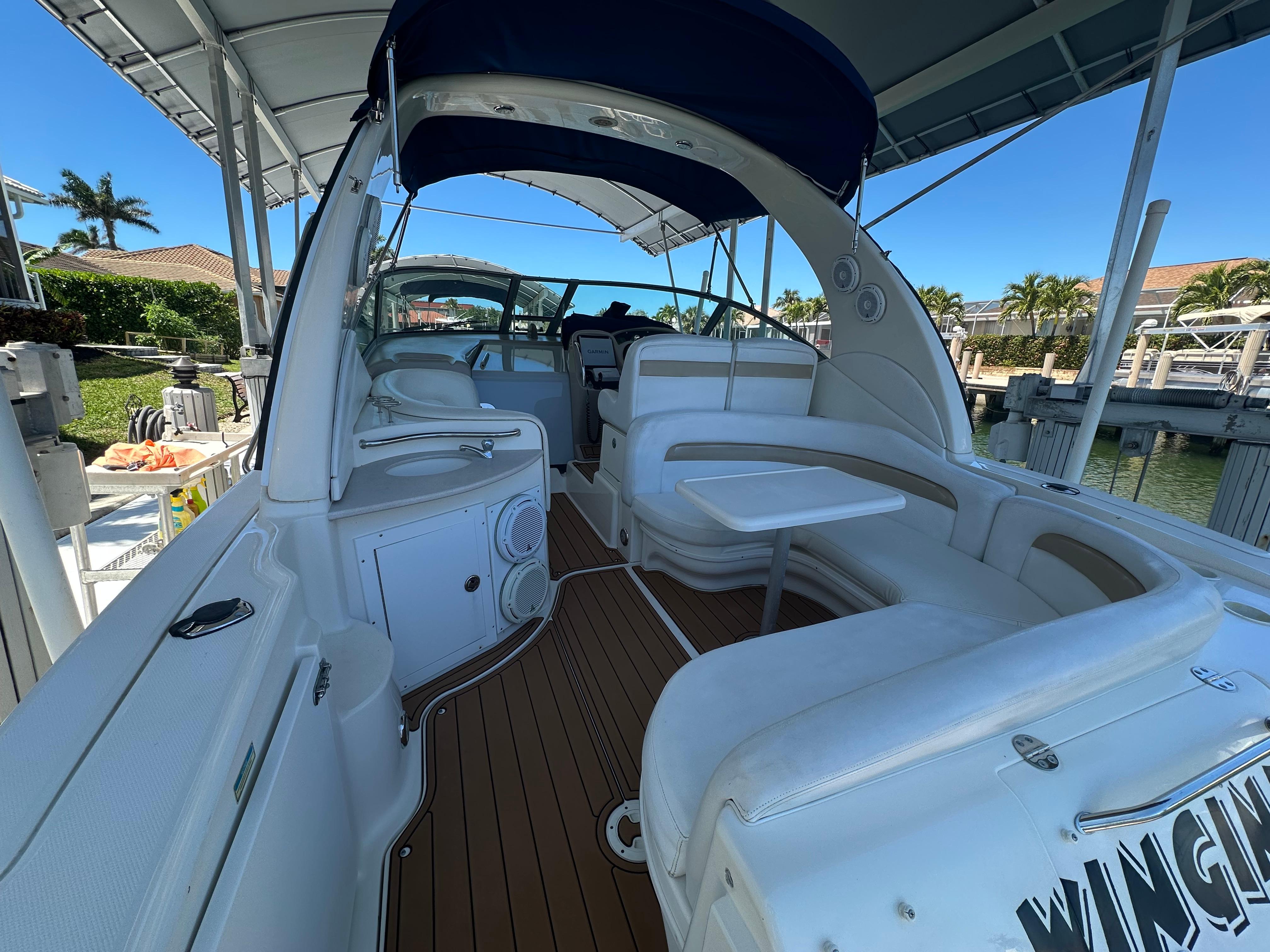 2005 Sea Ray 320 Sundancer boat interior with seating and table under canopy.