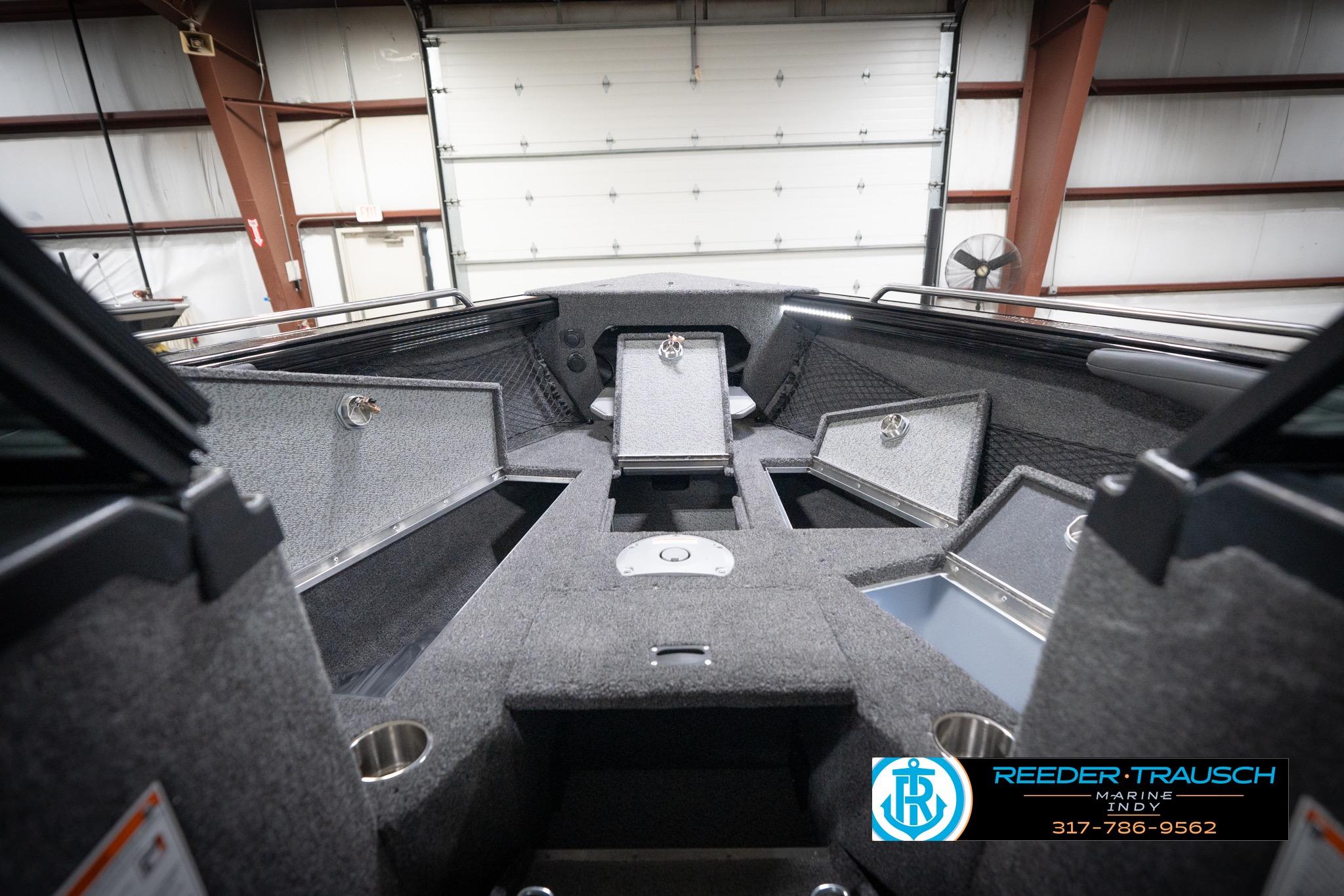2026 Lund 2275 Baron boat interior with storage compartments in a showroom.