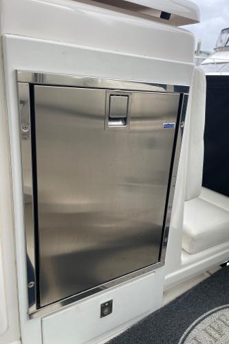 Stainless steel refrigerator door on a boat, surrounded by white upholstery.