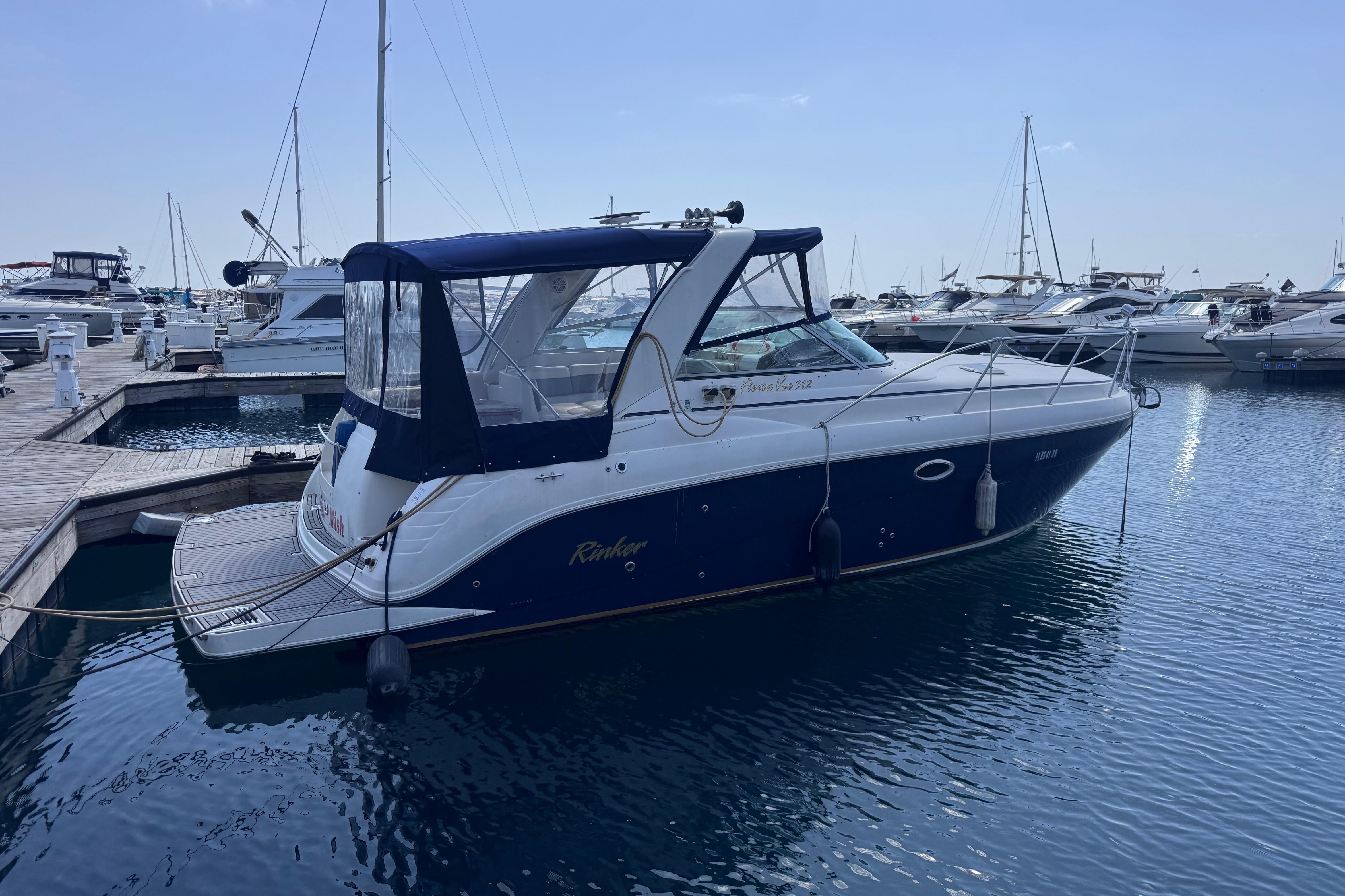 2003 Rinker Fiesta Vee 312 boat docked at marina, calm water, clear sky.