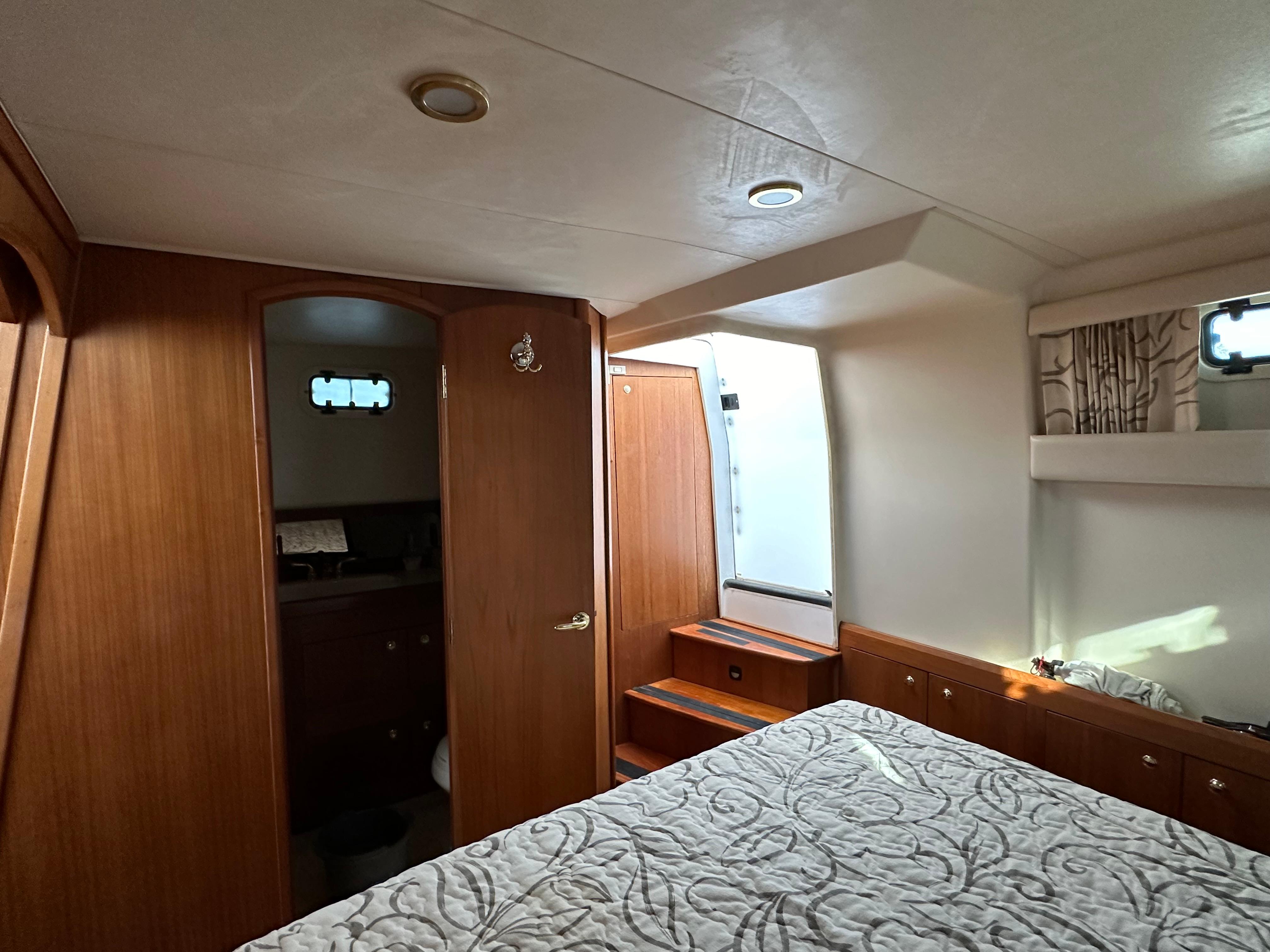 Aft cabin interior of 2000 Mainship 43 Trawler, featuring wood paneling and a cozy bed.