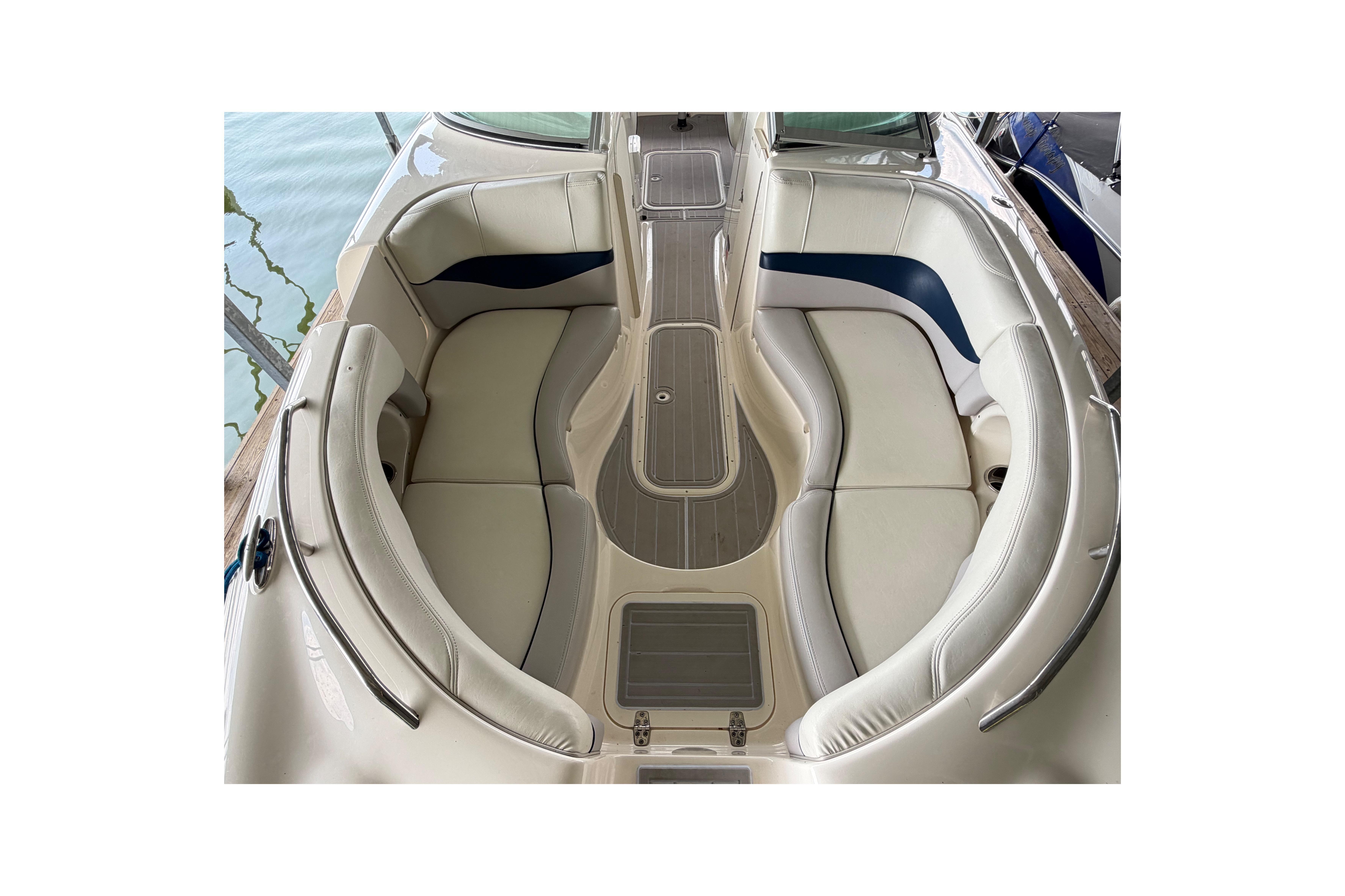 2010 Bryant 255 boat interior with white and blue seating, docked by the water.
