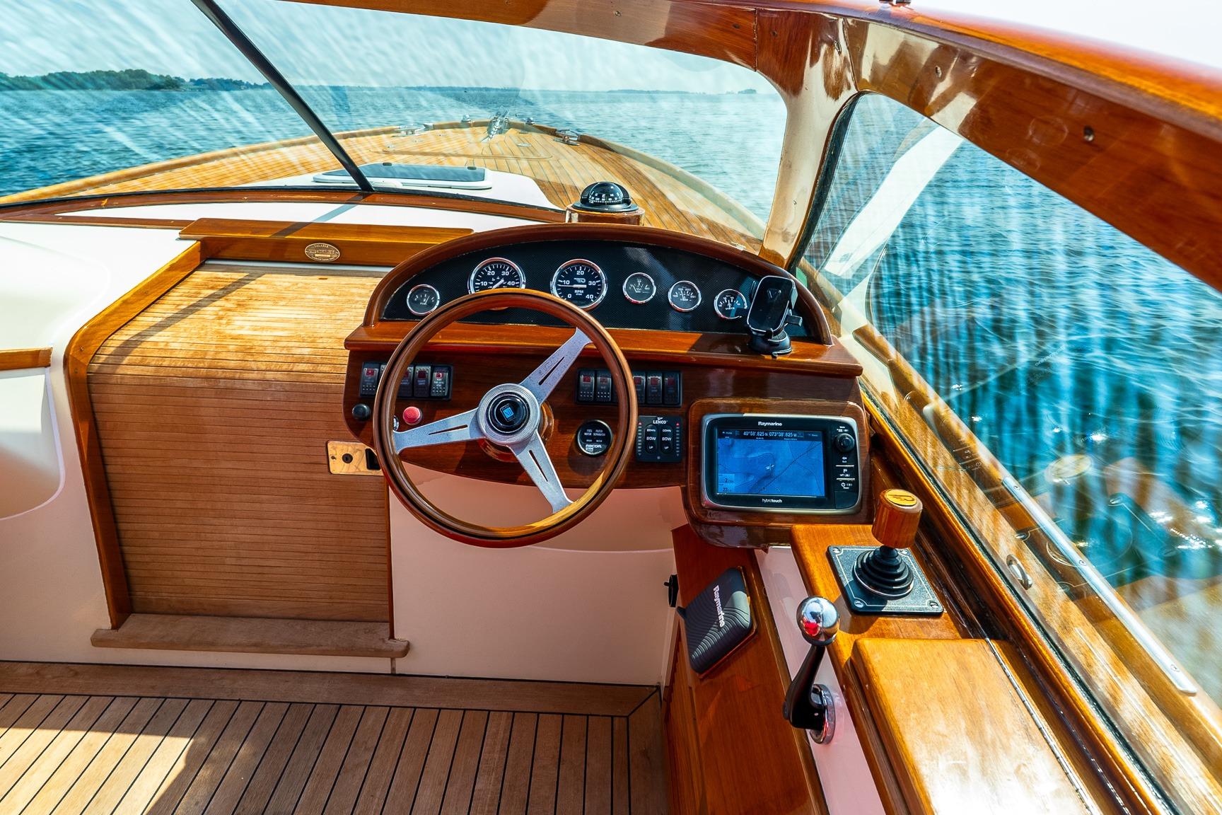Interior view of a 2005 Hinckley Talaria 29R boat cockpit with wooden steering wheel.