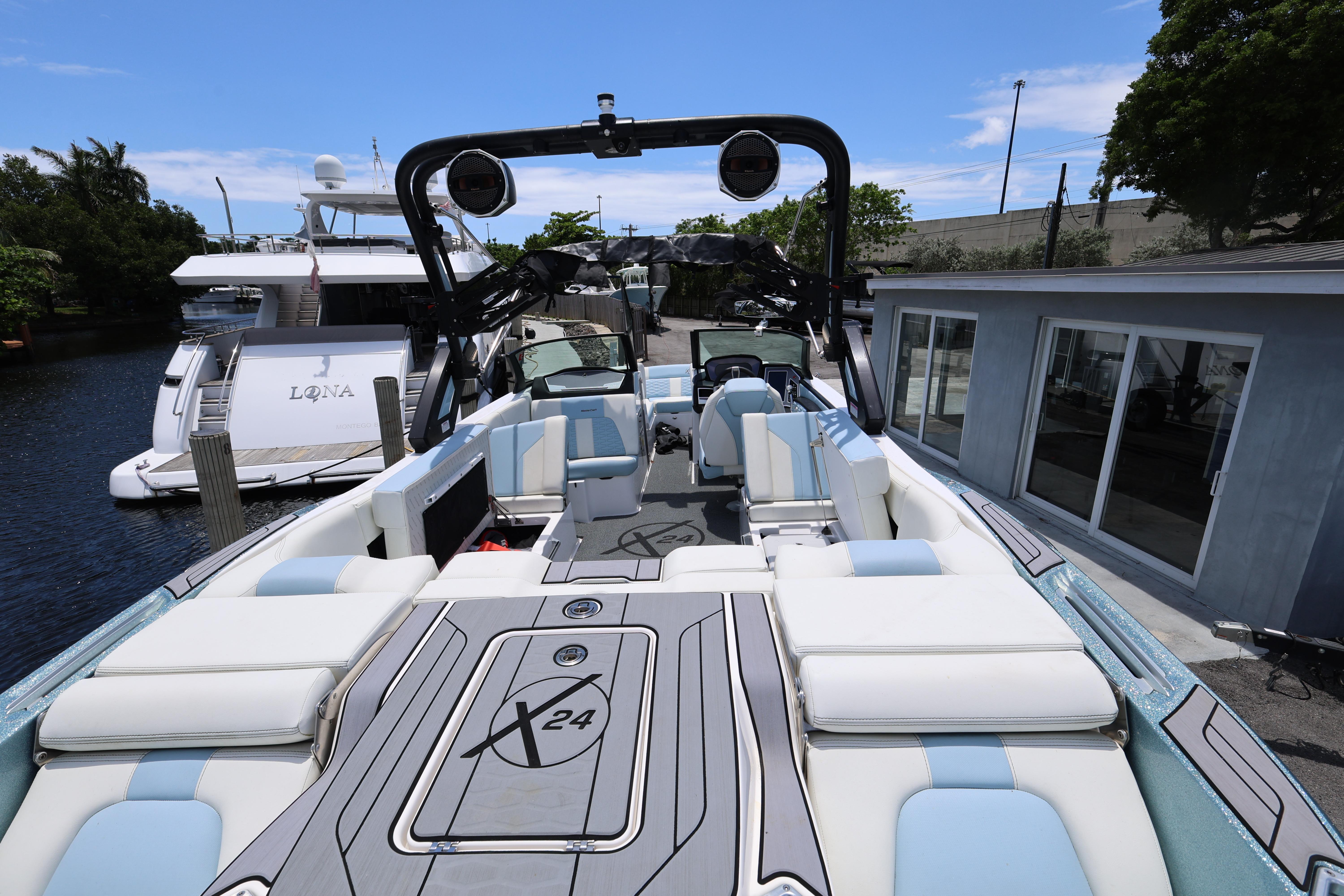 2023 MasterCraft X24 boat with luxurious seating and sleek design docked by the water.