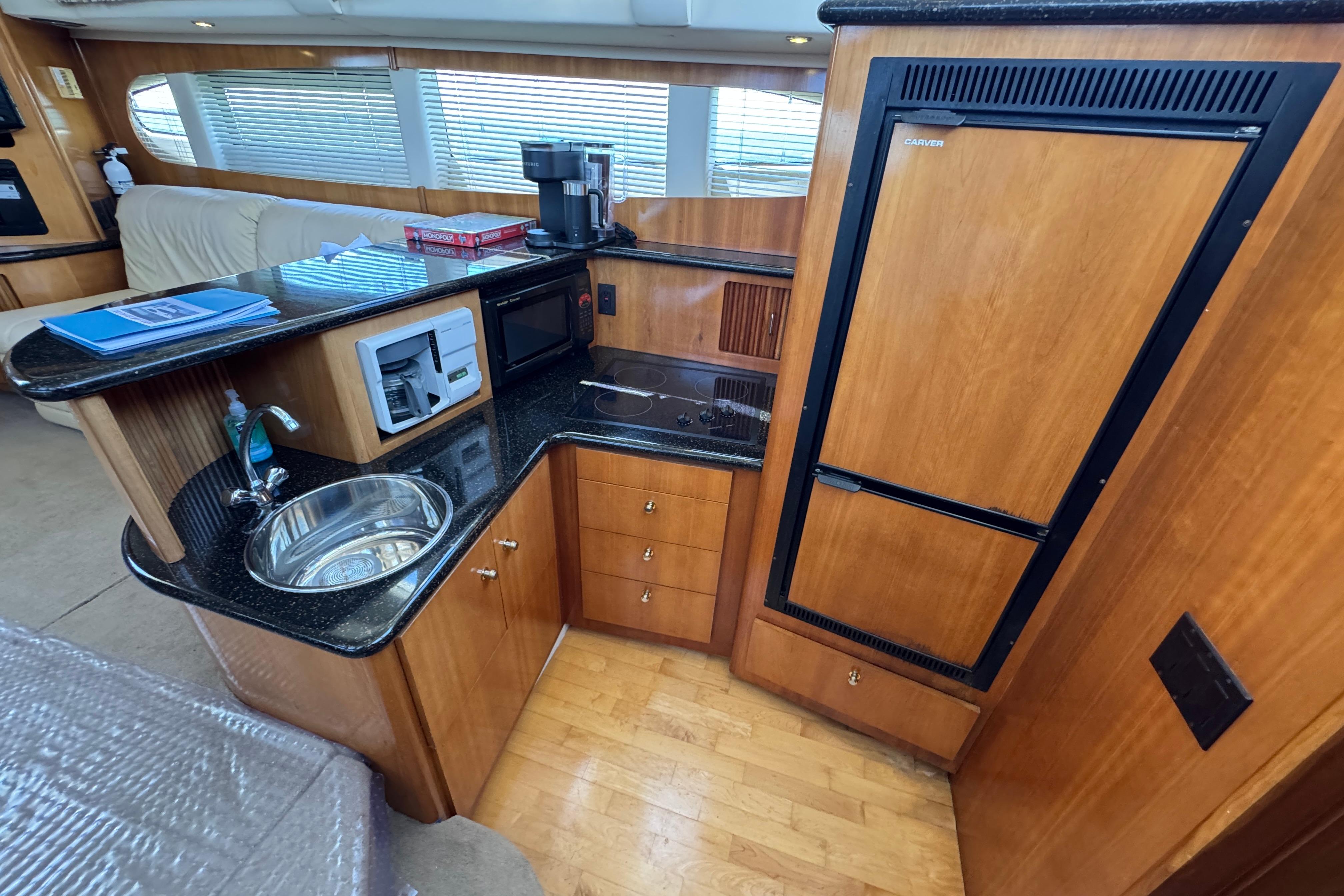 2002 Carver 396 Motor Yacht kitchen with wood cabinetry, sink, microwave, and refrigerator.