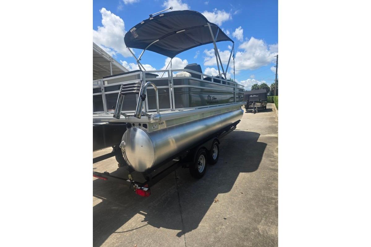 2026 Sun Tracker Fishin' Barge 22 DLX pontoon boat with canopy on trailer.
