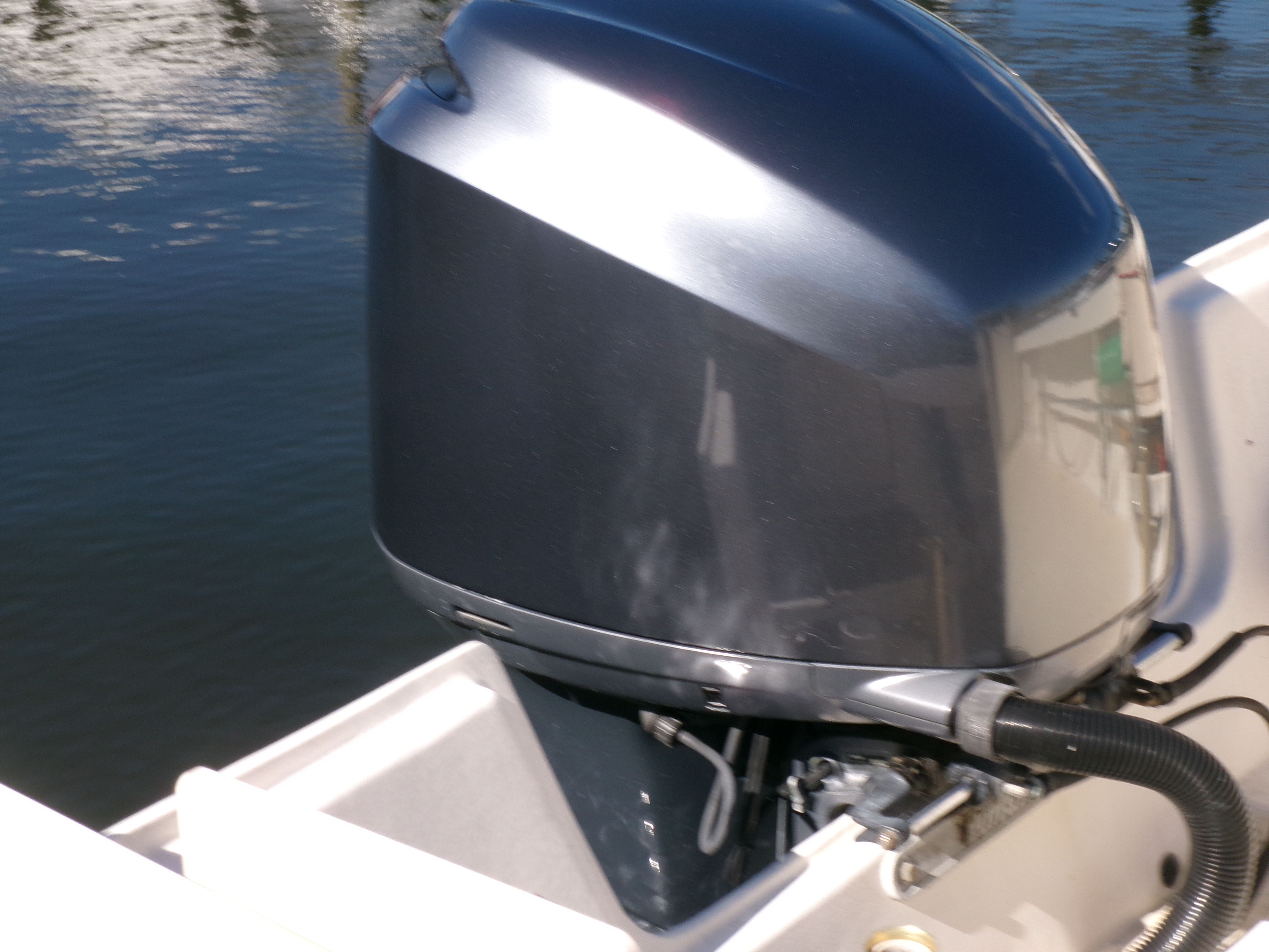 An outboard motor on a boat in the water. The motor is dark gray.
