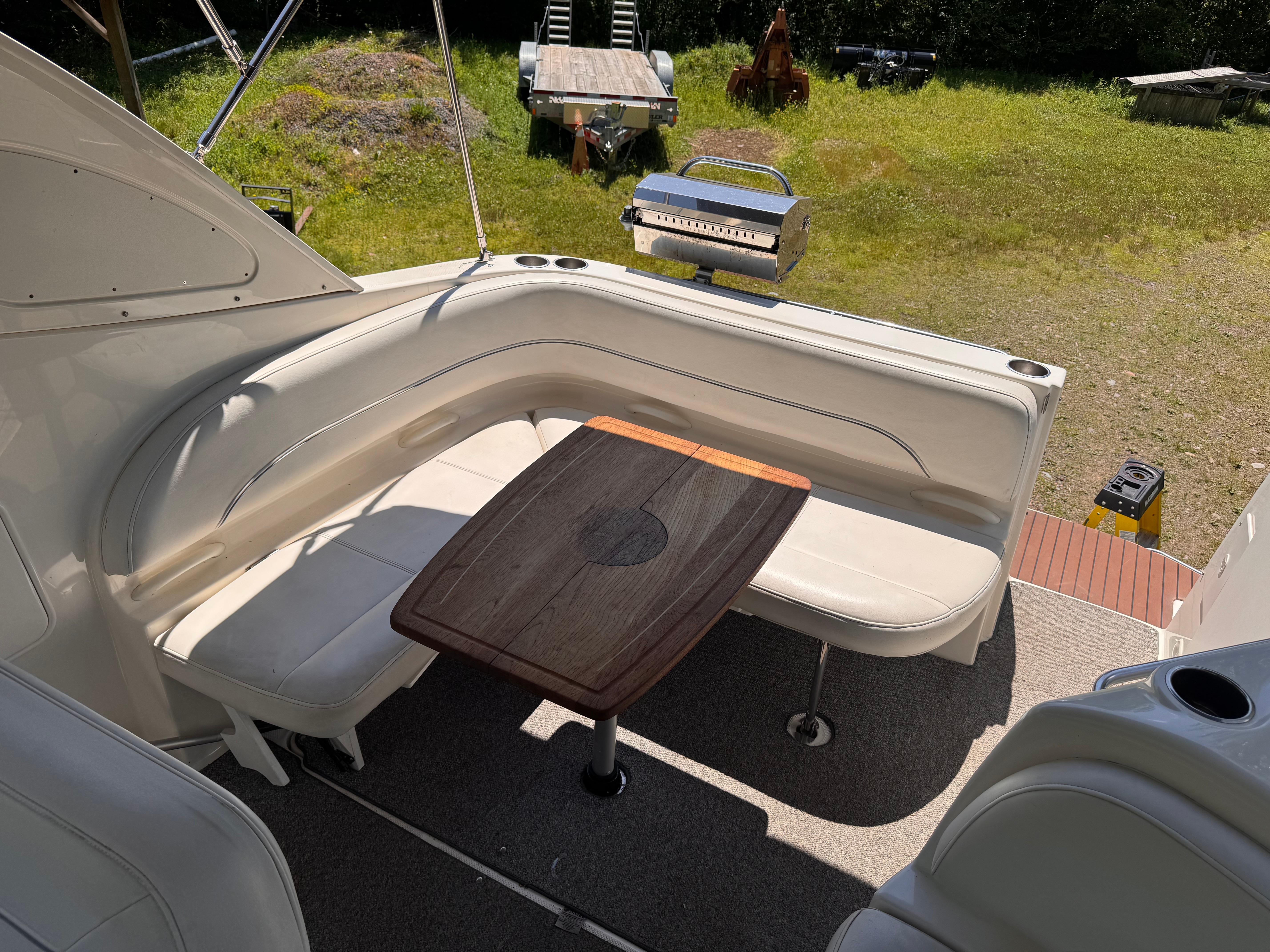2009 Bayliner 300 boat interior with seating and wooden table, set in a grassy outdoor area.