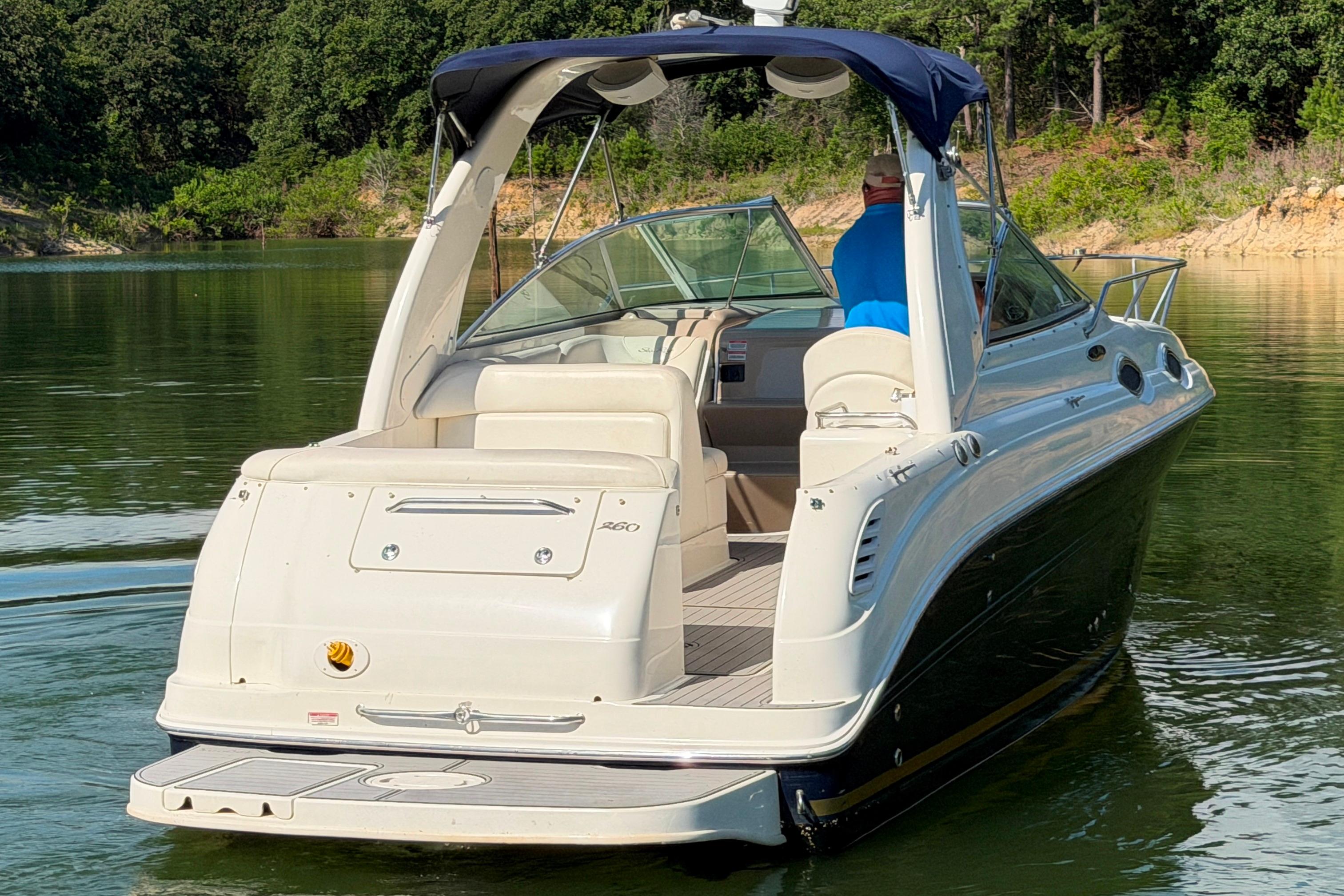 2004 Sea Ray Sundancer 260 boat cruising on a serene lake with lush greenery.