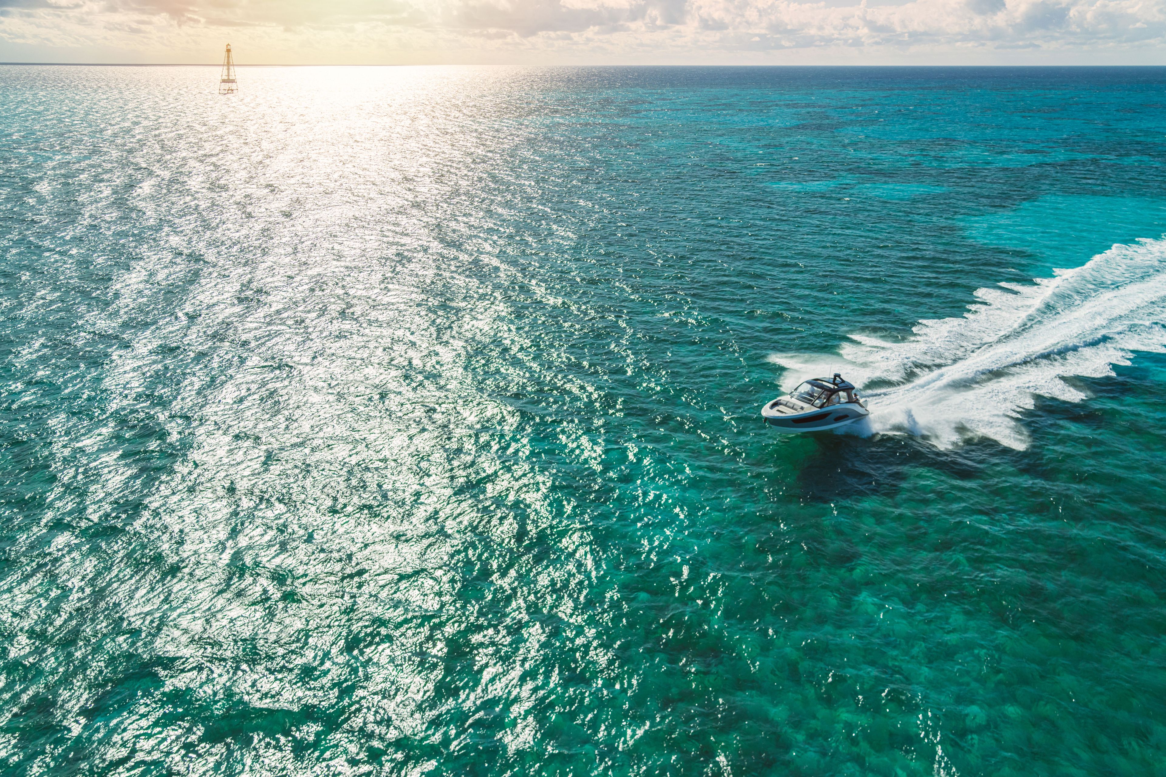 Sea Ray Sundancer 370 Outboard glides over turquoise water under a sunny sky.