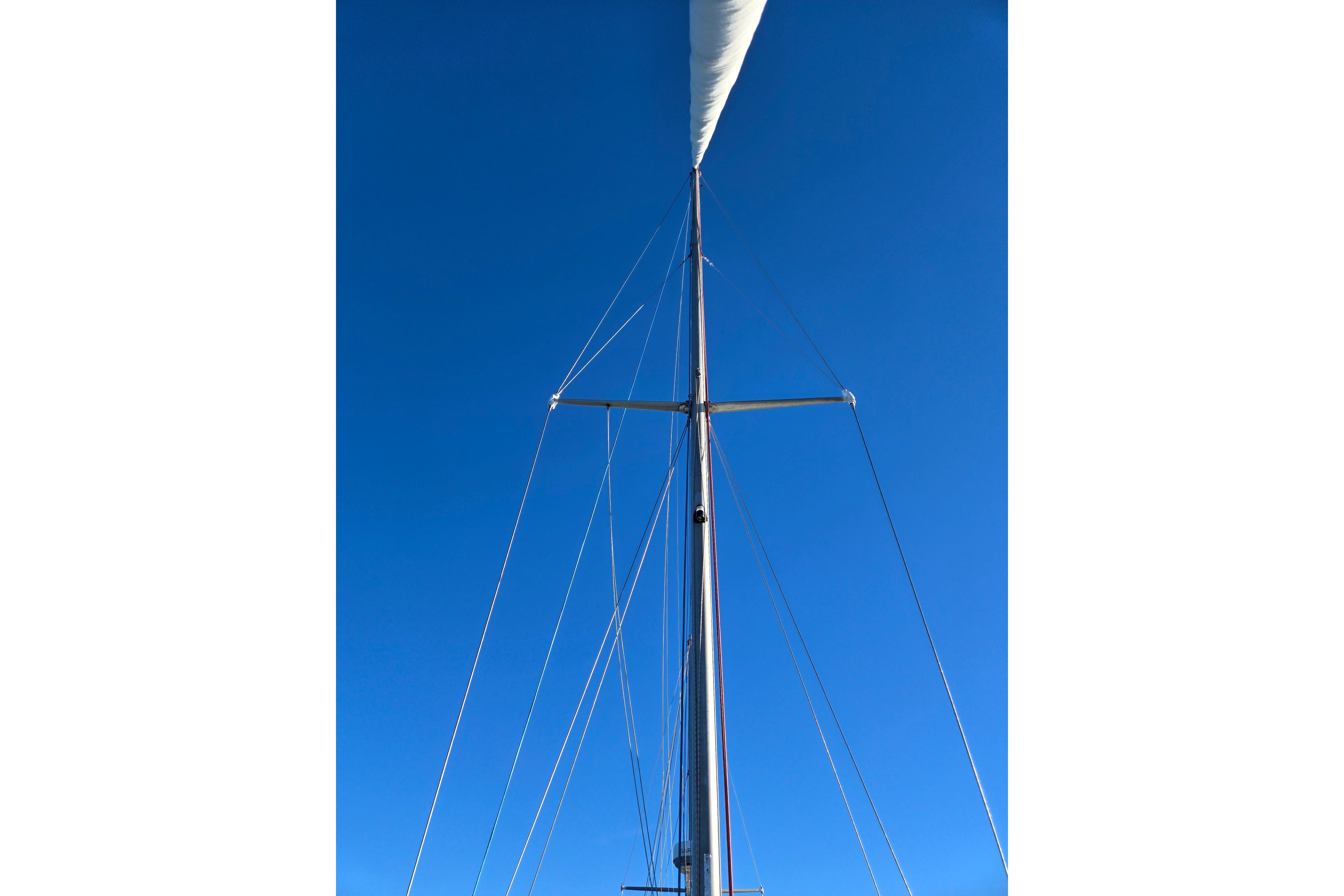 Mast of a 1970 Hinckley Bermuda 40 sailboat against a clear blue sky.