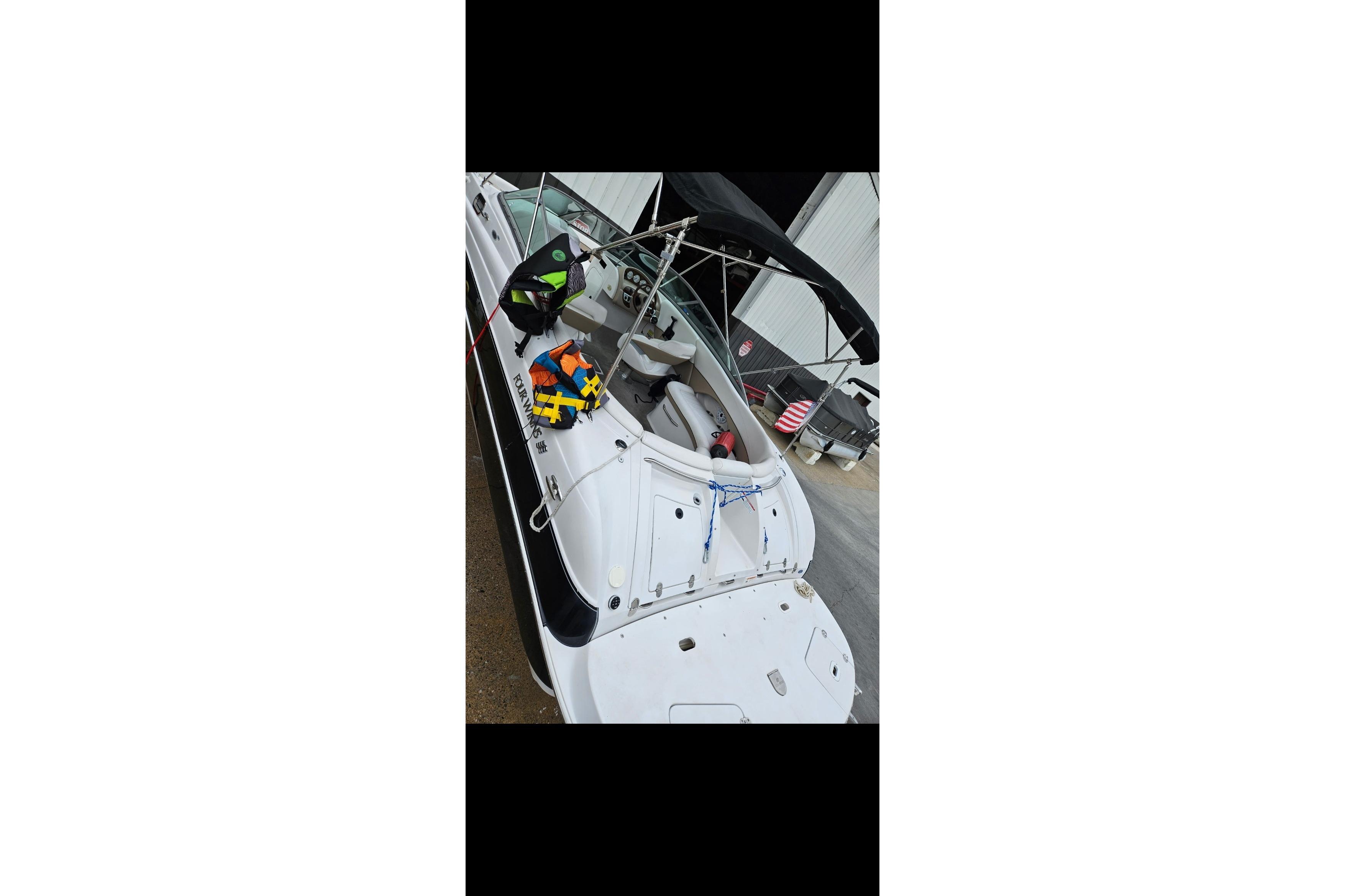 2006 Four Winns 244 Funship boat with canopy and life jackets docked at marina.