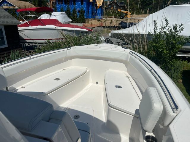 The image shows the bow of a 2023 Pursuit S268 boat, surrounded by greenery.