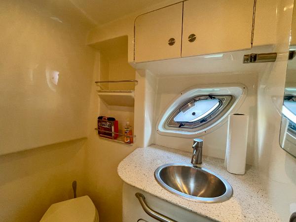 2014 Sea Ray 330 Sundancer bathroom with sink, porthole, and storage cabinets.