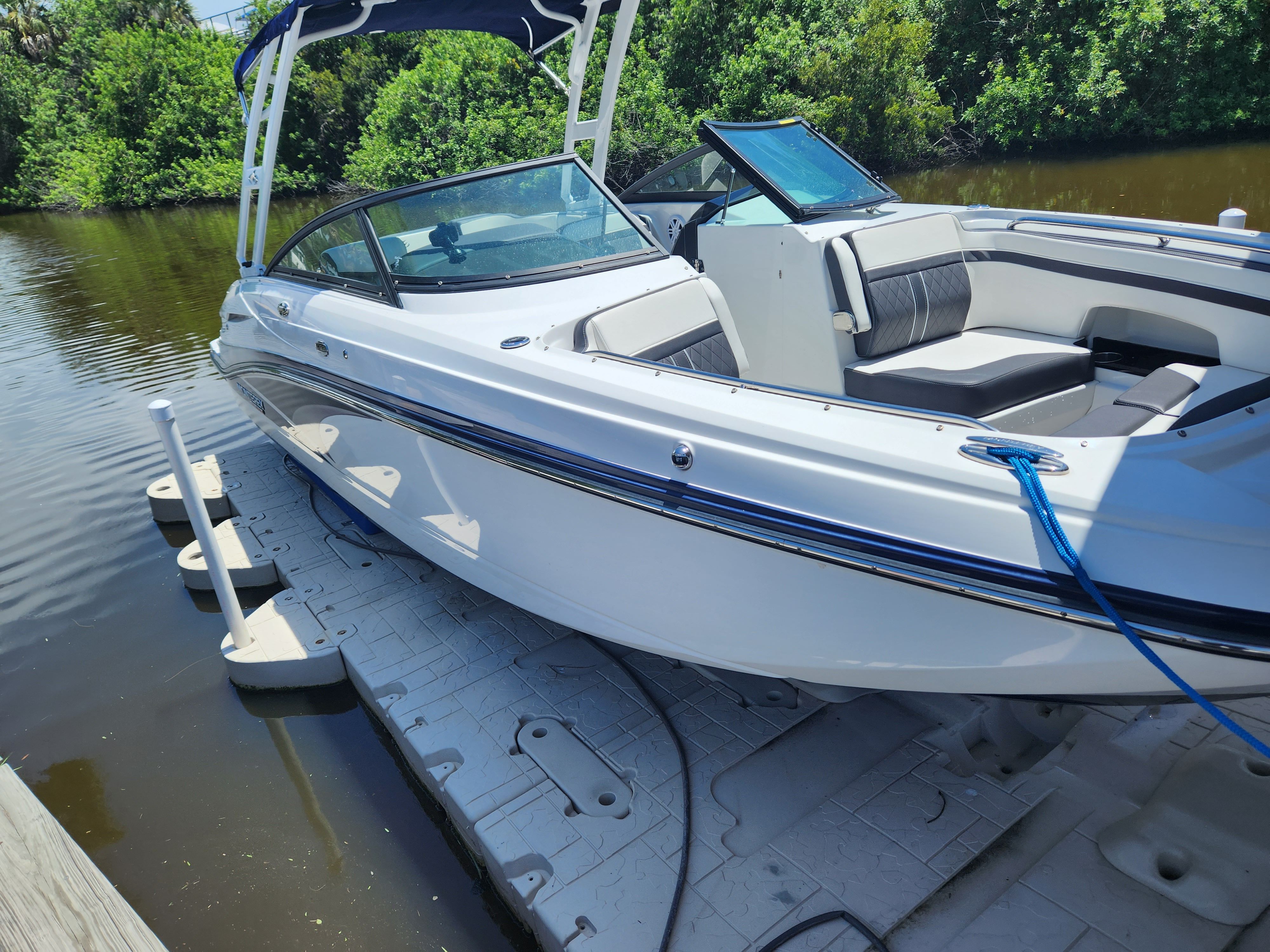A white 2021 Monterey M6 boat docked, featuring a blue canopy and sleek design.