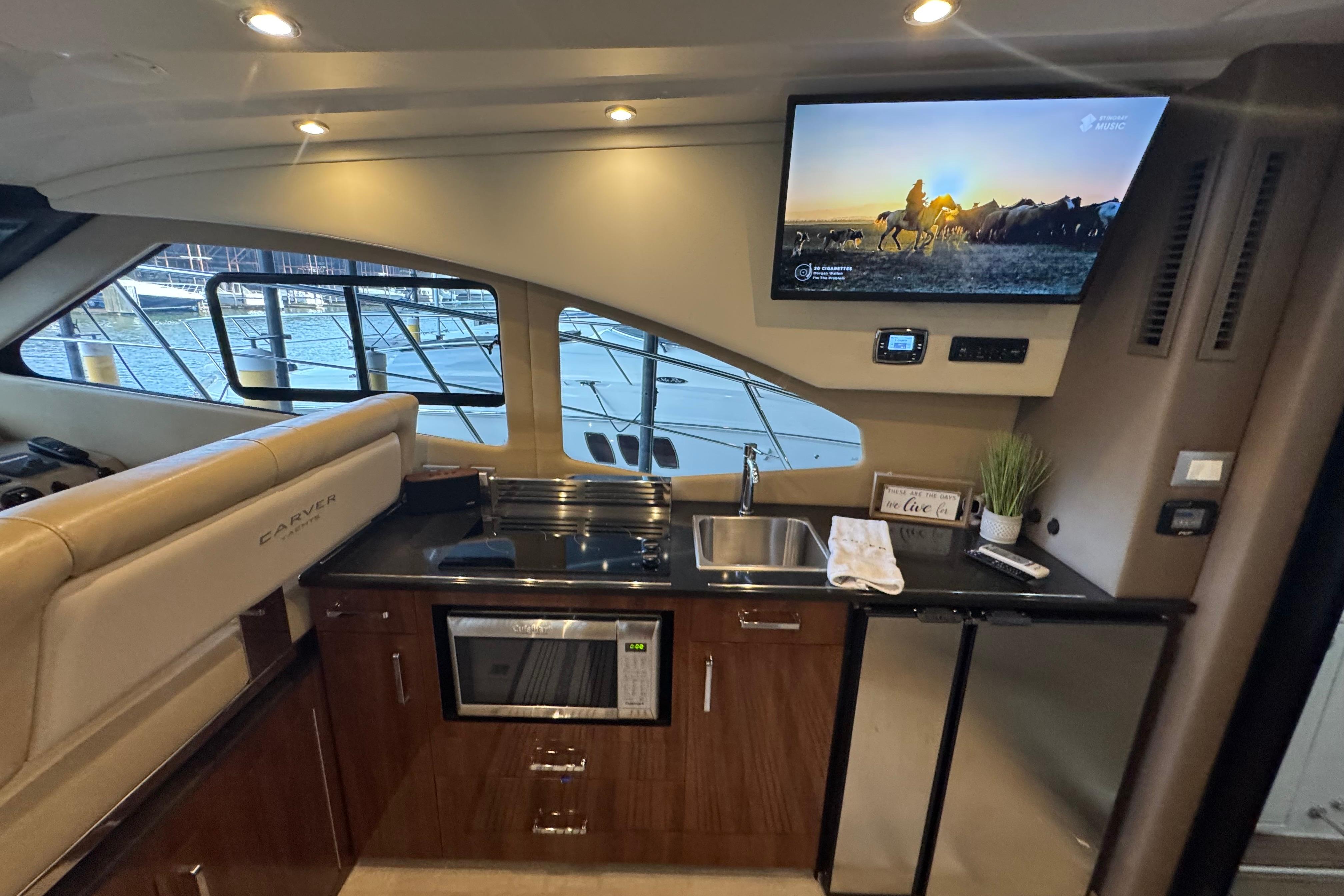 Interior of 2016 Carver C37 Coupe yacht with kitchenette and mounted TV.