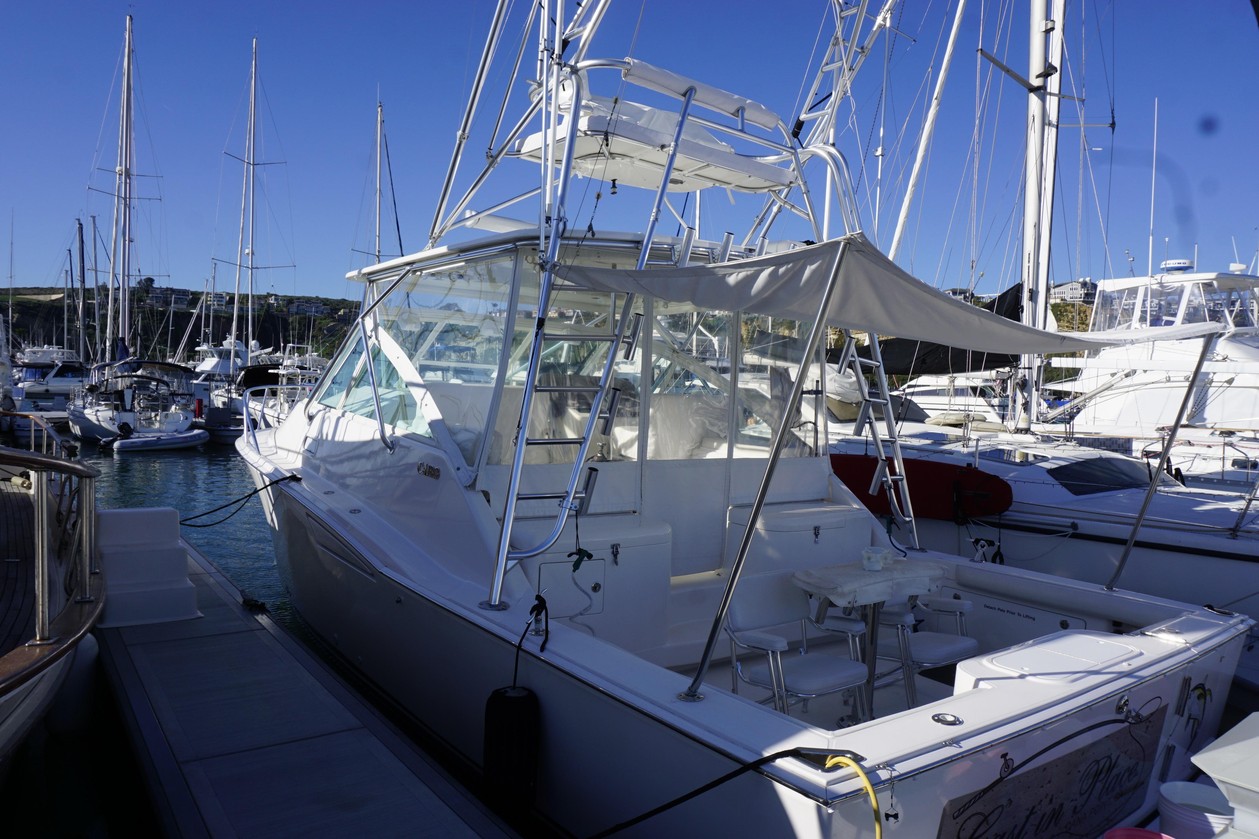 2005 Cabo 35 Express yacht docked in a marina, surrounded by sailboats.