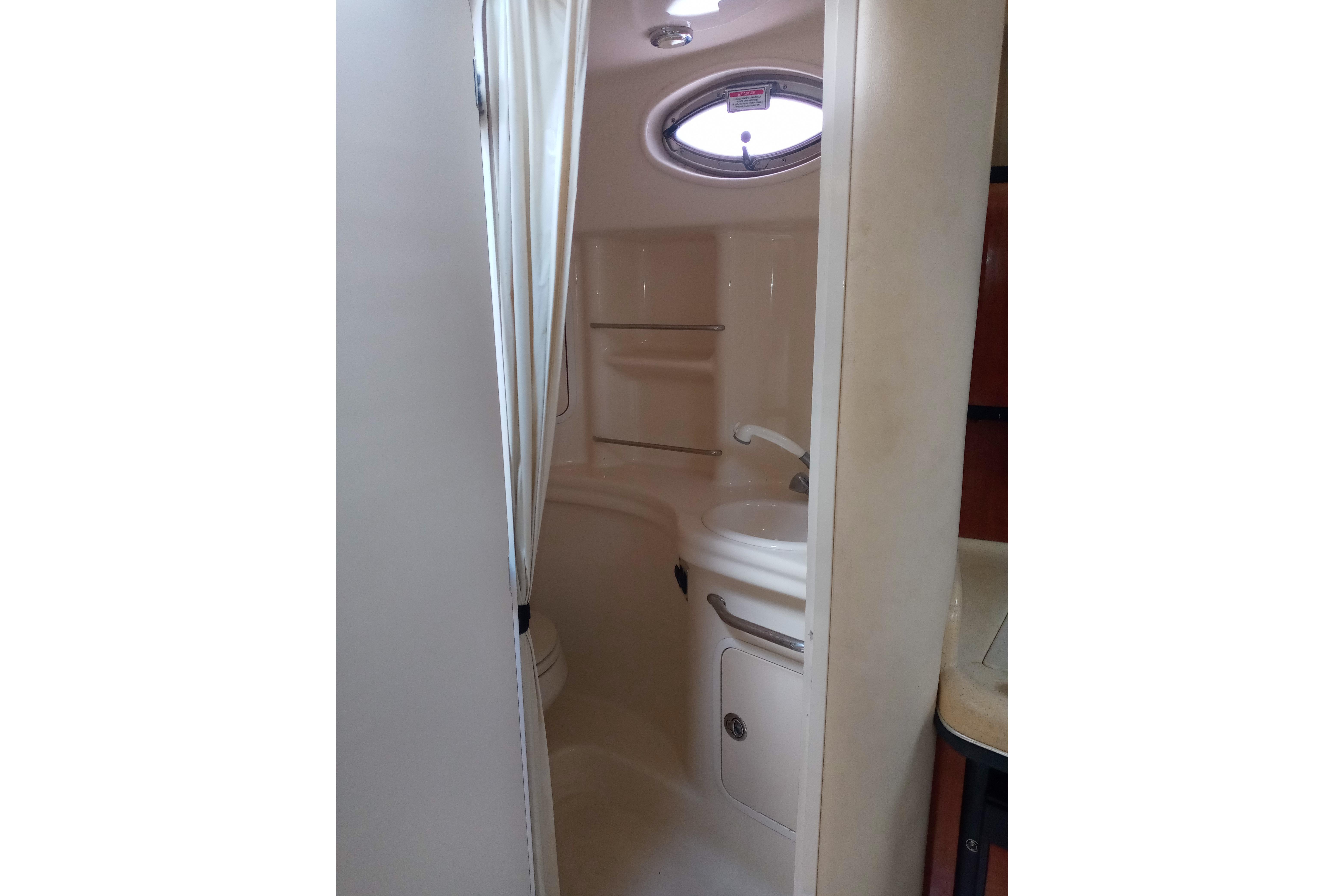 2005 Sea Ray 300 Sundancer bathroom with sink, toilet, and porthole window.
