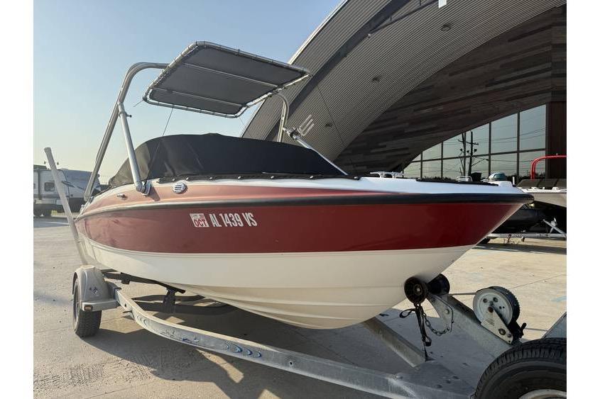 2008 Bayliner 185 Bowrider boat on trailer, red and white, parked outdoors.