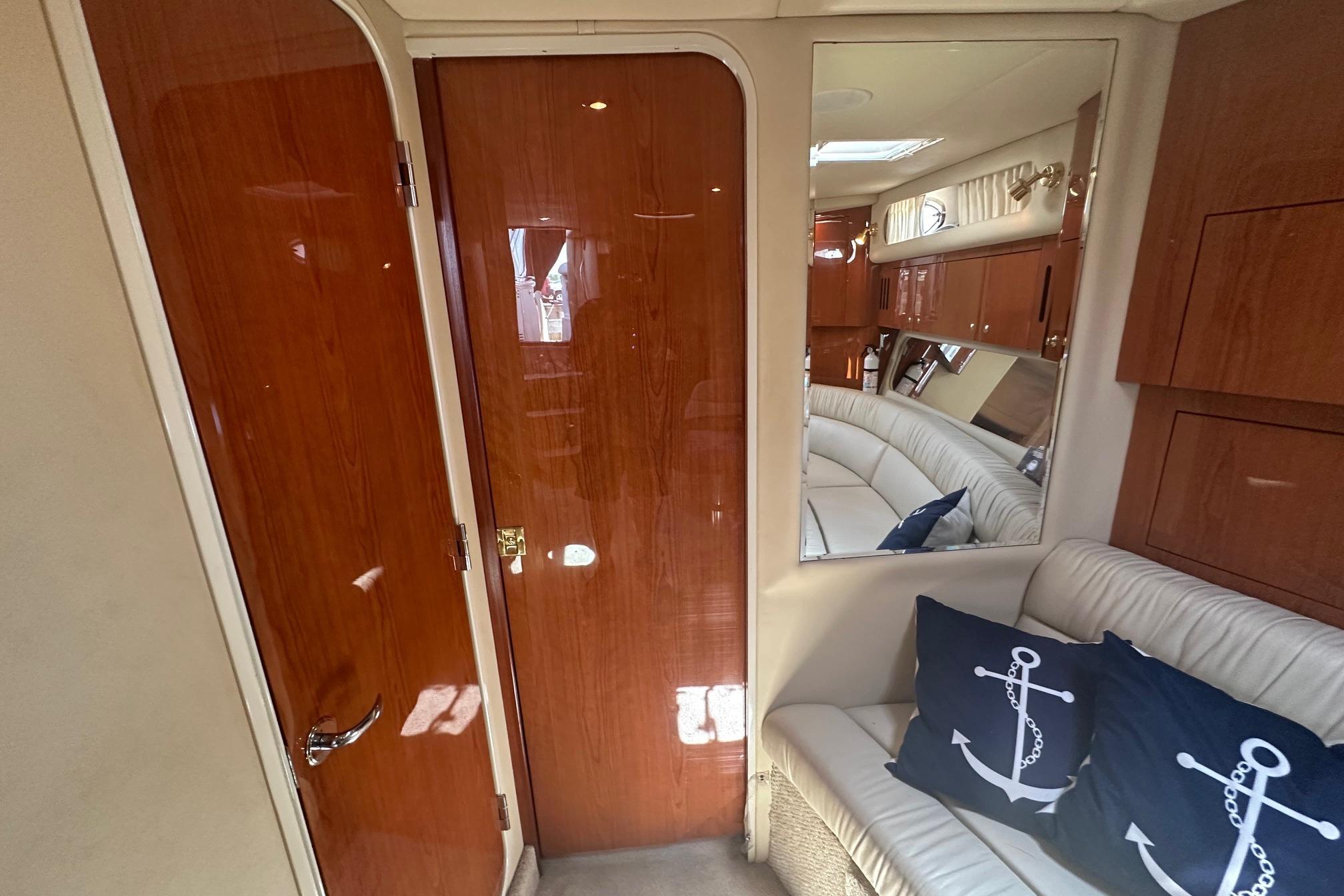 Interior of 2001 Sea Ray 410 Sundancer with wood paneling and nautical-themed cushions.